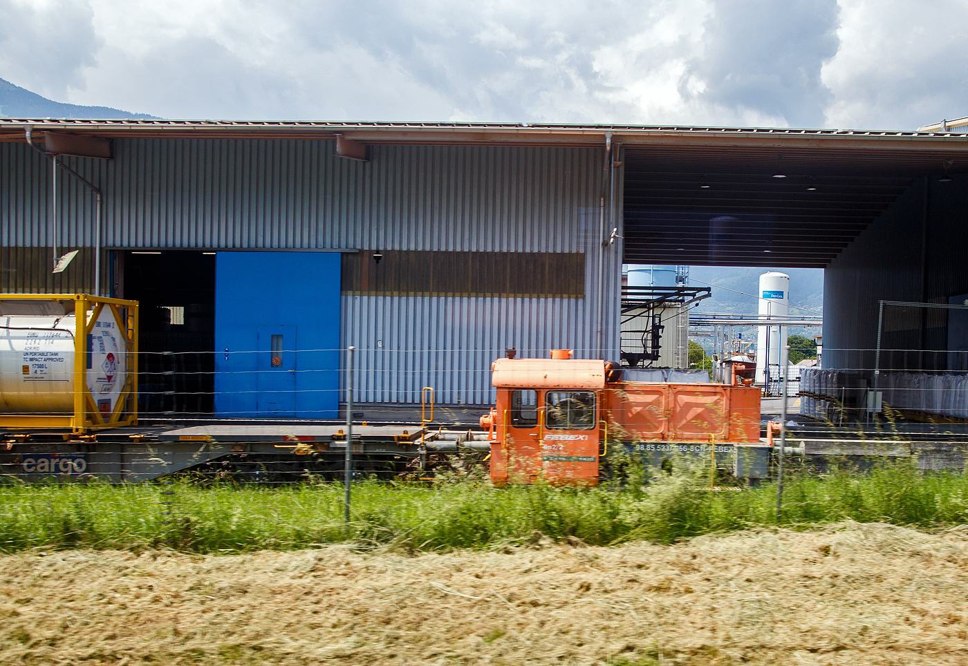 Die Tm 2/2 – Tm 237 956-8 (98 85 5237 956-8 CH-FEBE) der Febex S.A. in Bex, ex DB 323 085-1, DB Köf 6207 (eine Köf II), steht 28.05.2023 am Firmengelände in Bex (CH). Aufnahme aus einem Zug heraus.

Die Köf II wurde 1955 von Deutz (KHD) in Köln-Deutz unter der Fabriknummer 55754 gebaut. Die DEUTZ Typenbezeichnung war A6M 617 R, welches auch gleichzeitig die verbaute Deutz-Motortype war. Die Auslieferung an DB - Deutsche Bundesbahn erfolgte am 25.01.1955 als Köf 6207, mit der Einführung der EDV-Nummern erfolgte zum 01.01.1968 die Umzeichnung in DB 323 085-1, Ende 1987 erfolgte in Freiburg die Ausmusterung bei der DB. Im Juni 1990 wurde sie an die Mobil Oil Switzerland fürs Tanklager Auhafen in Muttenz (ab 1997 BSZ Oil AG) verkauft. Im Jahr 2002 ging sie LSB Lok Service Burkhardt AG, 2003 an die Tafag AG in Arth-Goldau als Tm 237 956-8, bis sie dann 2006 an die Febex S.A. in Bex ging.
