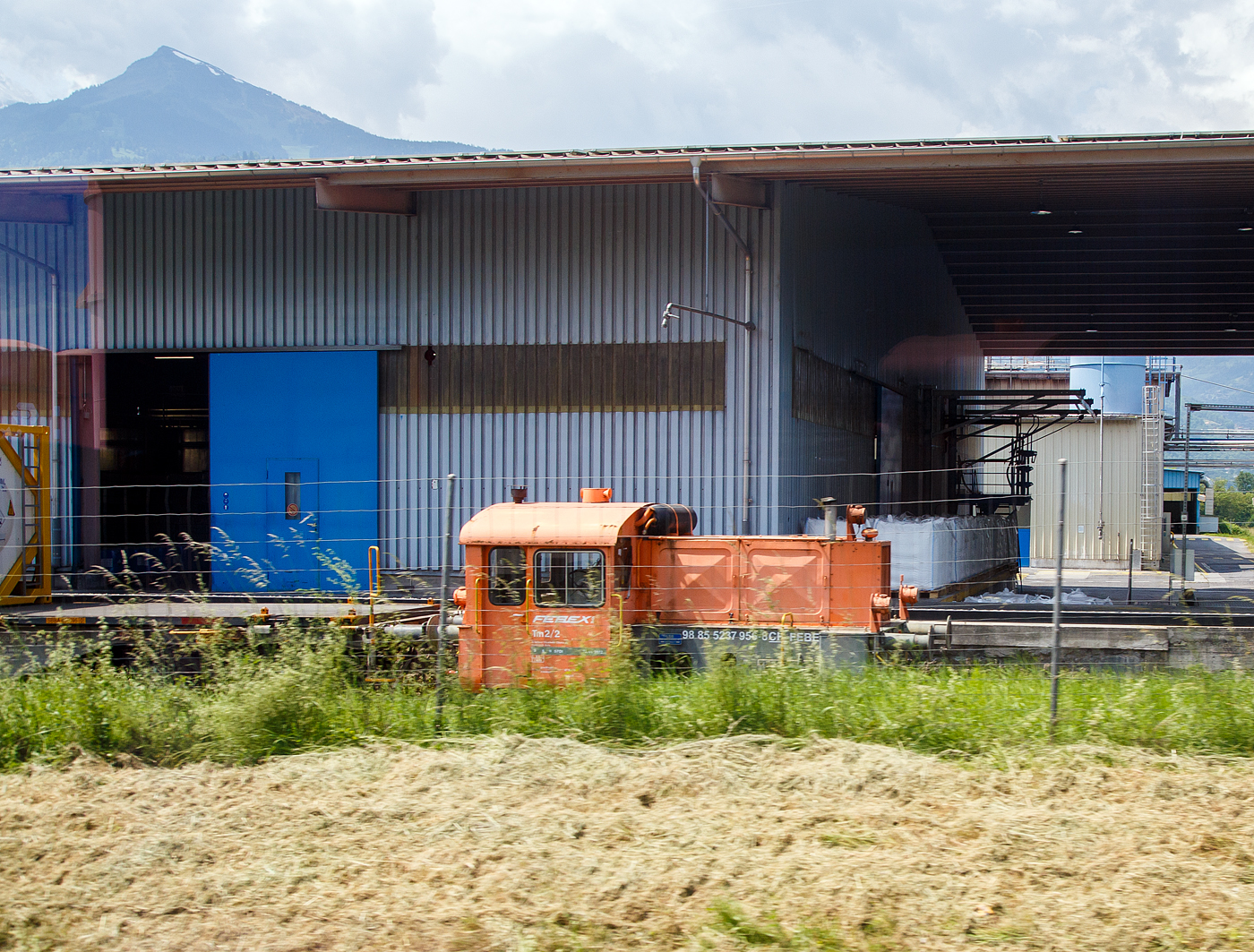 Die Tm 2/2 – Tm 237 956-8 (98 85 5237 956-8 CH-FEBE) der Febex S.A. in Bex, ex DB 323 085-1, DB Köf 6207 (eine Köf II), steht 28.05.2023 am Firmengelände in Bex (CH). Aufnahme aus einem Zug heraus.

Die Köf II wurde 1955 von Deutz (KHD) in Köln-Deutz unter der Fabriknummer 55754 gebaut. Die DEUTZ Typenbezeichnung war A6M 617 R, welches auch gleichzeitig die verbaute Deutz-Motortype war. Die Auslieferung an DB - Deutsche Bundesbahn erfolgte am 25.01.1955 als Köf 6207, mit der Einführung der EDV-Nummern erfolgte zum 01.01.1968 die Umzeichnung in DB 323 085-1, Ende 1987 erfolgte in Freiburg die Ausmusterung bei der DB. Im Juni 1990 wurde sie an die Mobil Oil Switzerland fürs Tanklager Auhafen in Muttenz (ab 1997 BSZ Oil AG) verkauft. Im Jahr 2002 ging sie LSB Lok Service Burkhardt AG, 2003 an die Tafag AG in Arth-Goldau als Tm 237 956-8, bis sie dann 2006 an die Febex S.A. in Bex ging.
