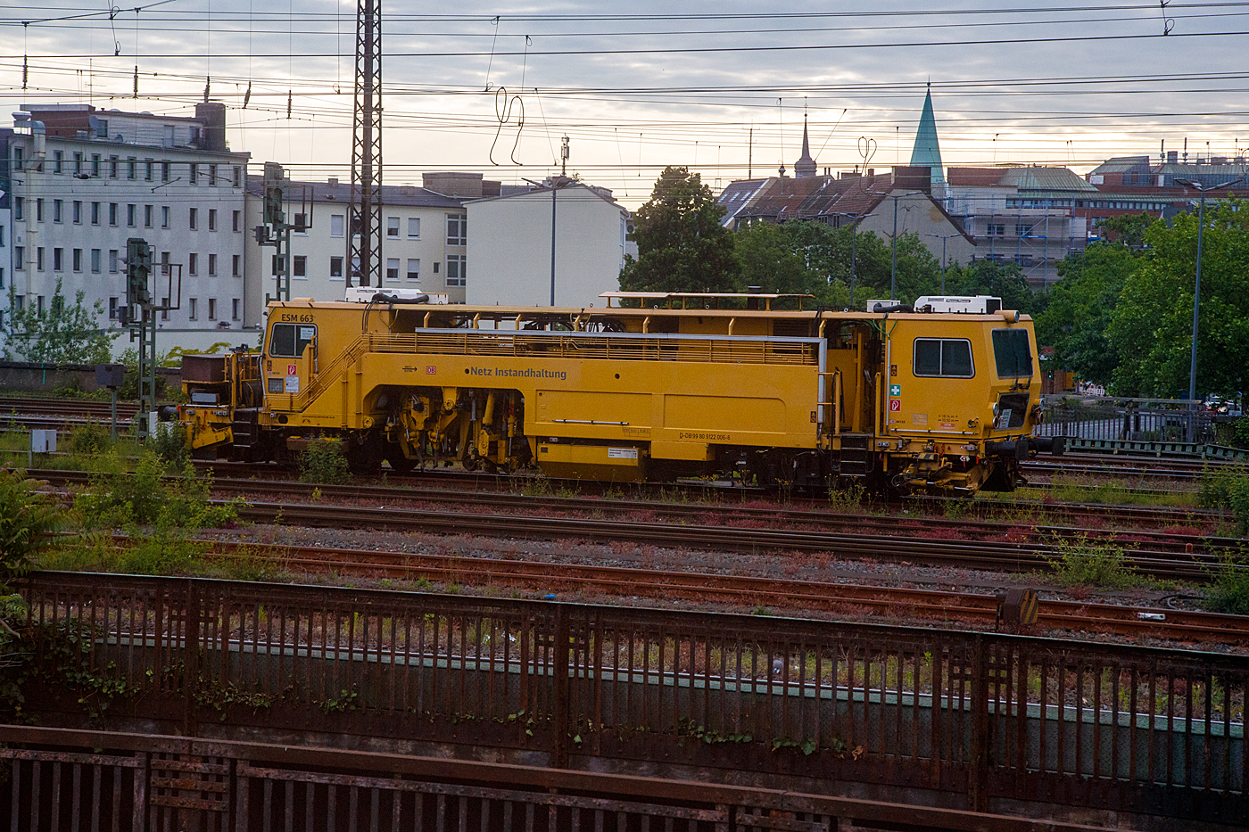 Die Universal-Stopfmaschine UNIMAT-Sprinter ESM 663 der DB Netz AG, D-DB 99 80 9122 006-5 (ex Schweres Nebenfahrzeug Nr. 97 43 52 005 17-3) ist am 31.05.2022 beim Hbf Hamm (Westf.) abgestellt: Aufnahme aus einem IC heraus.

Der Unimat-Sprinter ist eine von Plasser und Theurer entwickelte Stopfmaschine für Gleise, Weichen und Kreuzungen, speziell konzipiert für die rasche und präzise Behebung von Einzelfehlern. Daher auch die Abkürzung ESM = EinzelfehlerStopfMaschine. Diese hier wurde 2000 von Plasser & Theurer in Linz (A) unter der Fabriknummer 1168 gebaut.