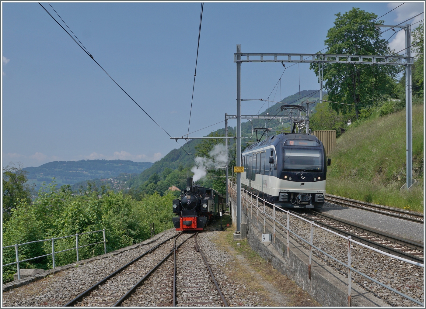 Durch die Gr�sse des Bahnhofs Chamby und des Betriebsgeschehen ein eher seltenes Ereignis: Paralleleinfahrt des MOB GoldenPass Panoramic 2221 mit dem Alpina ABe 4/4 9303 und dem Blonay-Chamby Dampfzug mit der SEG G 2x 2/2 105.

28. Mai 2023