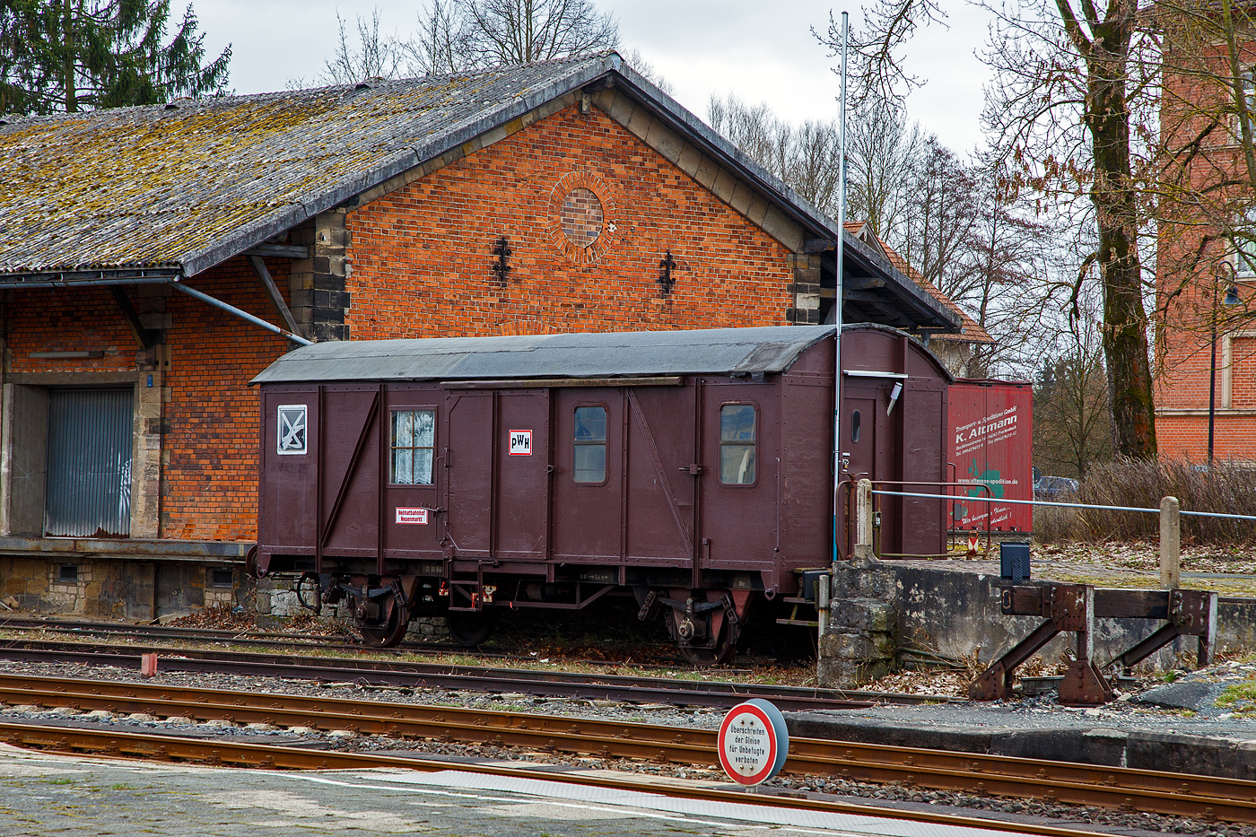 Ehemaliger zweiachsiger Güterzugbegleitwagen mit Bremserbühne, ex D-DB 20 80 950 5 078-6 der Gattung/Bauart Pwghs 054 der Deutschen Bundesbahn (ex Passau Hbf), am 26.03.2016 abgestellt beim Güterschuppen beim Bahnhof Neuenmarkt-Wirsberg.

Die Reichsbahn machte es im Kriege vor, aus dem laufenden Programm zum Bau gedeckter Güterwagen wurde ein Güterzugpackwagen abgeleitet. Neben dem eingesparten Konstruktionsaufwand war dieses Mal auch ein Ziel, die Wagen leicht wieder als normale gedeckte Güterwagen herzurichten, wenn sie als Pwghs nicht mehr benötigt werden, das hat man dann auch bei 2/3 der Pwghs tatsächlich auch so gemacht. Mitte der 50er Jahre war es soweit: Die meisten neuen Güterwagen waren für 100 km/h zugelassen, die neuen Loks wurden immer schneller- aber es fehlten eklatant die zugehörigen Güterzuggepäckwagen. Viele Güterzüge sollten 80 km/h und mehr fahren können. Die meisten vorhandenen Packwagen für diesen Zweck stammten noch aus der Länderbahnzeit, hatten schon mehr als 40 Jahre auf dem Buckel, waren aber nur für 65 km/h zugelassen.

Die Vorgängerbauart Pwgs 44, die 100 km/h fahren durfte, hatte einen grundlegenden konstruktiven Mangel: Die Federung der Wagen war für einen beladenen Güterwagen mit 20 t und mehr ausgelegt, der Wagen konnte aber nur mit 5 t beladen werden. So war die Federung hart und das Zugbegleitpersonal klagte über das Rütteln und Schaukeln des Wagens.

Um Abhilfe zu schaffen, mussten doch neue Pwgs her. Es sollten aber keine richtigen Packwagen werden, sondern auch die Option eines einfachen Rückbaus haben, denn der Strukturwandel zeichnete sich schon ab. Eines Tages braucht man in Ganzzügen gar keinen Pwg mehr, der Zugführer konnte auf der Lok mitfahren. Also griff man, wie beim Pwgs 44, auf eine parallele Güterwagenkonstruktion zurück, diesmal auf den Gms 54, der in den AWs grade gebaut wurde. 

Der neue Pwghs 54 bekam eine besondere Inneneinrichtung mit Zugführerabteil und einer Toilette, die leicht wieder abbaubar waren. Die Stromversorgung erfolgte über ein Kabel, das an die Lok angeschlossen wurde, auch die Heizung kam von der Lok. Im Bereich des Zugführerabteils bekam der Wagen je zwei Fenster, die praktischerweise aus dem laufenden Programm 3-achsigen Umbauwagen stammten. 

1957 war es soweit: Das AW Fulda durfte einen Musterwagen bauen. Nach Erprobung und kleinen Änderungen fertigte das AW München-Freimann im laufenden Gms 54- Programm die neuen Güterzugpackwagen. Insgesamt 1.200 Wagen wurden gebaut. Als Spenderfahrzeuge kamen nicht nur die G 02 und G 10 in Frage, sondern auch die älteren Pwg pr 12 und 14. Viele Neubauten des Pwghs 54 bekamen zuerst das rote E-Schild für den Einsatz im Eilgüterverkehr. Erst spätere Lieferungen bekamen das Sonderzeichen nicht mehr.

Ab1970 brauchten immer weniger Eilgüterzüge einen Pwghs, weil immer mehr Güterzüge von Elloks bzw. Dieselloks gezogen wurden. Da konnte der Zugführer auf der Lok mitfahren. Die E-Pwghs 54 verloren so ihre besondere Kennzeichnung und konnten als normale Güterzugpackwagen auch im Nahbereich eingesetzt werden. Die Wagen trugen auf der Stirnseite bzw. Ladetür den Namen des Heimatbahnhofes. Im Laufe der Zeit wurden immer mehr Pwghs 54 überflüssig und konnten wie geplant zu Gms 54 umgebaut werden. Mehr als die Hälfte der noch vorhandenen Pwghs wurden umgebaut und Ende 1978 gab es nur noch knapp 200 Wagen, die vereinzelt noch weitere 20 Jahre Einsatz vor sich hatten. Knapp 200 Wagen wurden nach der Ausmusterung als Bahndienstwagen weiterverwendet.

TECHNISCHE DATEN:
Spurweite: 1.435 mm
Anzahl der Achsen: 2
Länge über Puffer: 11.140 mm
Achsabstand: 5.840 mm
Eigengewicht: 12.200 kg
max. Zuladung: 6.000 kg
zul. Höchstgeschwindigkeit: 100 km/h  