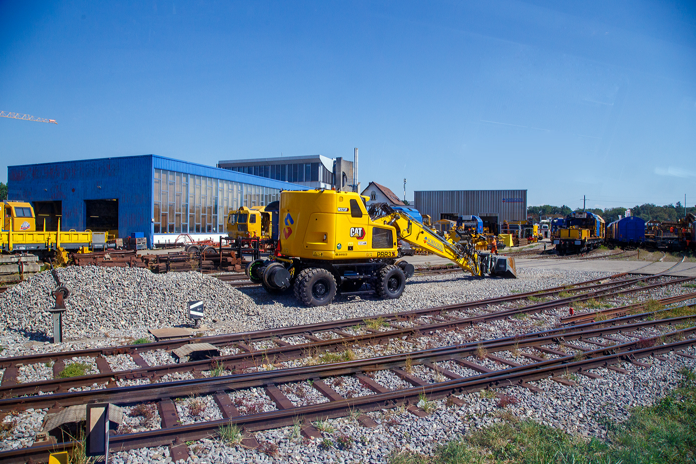 Ein Blick auf das Firmengelände der Scheuchzer SA in Bussigny (VD / Kanton Waadt) am 07 September 2023 aus einem Zug heraus.

Im Vordergrund der Scheuchzer PRR3, ein Zweiwegebagger mit hydrostatischem Schienenradantrieb vom Typ Caterpillar CAT M323F.