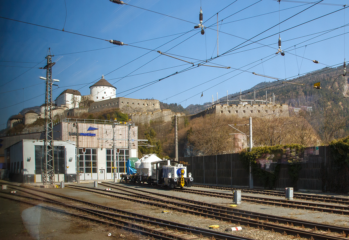 Ein Blick aus unseren EC 86, die Zebra-K�f III (mit Gelenkwellen) 333 716-9 „Wera“ (98 80 3333 716-9 D-LM) der Lokomotion Gesellschaft f�r Schienentraktion mbH, ex DB 335 216-8, ex DB 333 216-0, steht am 28 M�rz 2022 mit einem kurzen G�terzug bei der Lokomotion Lokwerkstatt in Kufstein. 

Die K�f der LG III (mit Gelenkwellen) wurde 1977 von O&K (Orenstein und Koppel) in Dortmund unter der Fabriknummer 26926 gebaut und als 333 216-0 an die Deutsche Bundesbahn geliefert. 1989 erfolgte die Ausr�stung mit Funkfernsteuerung und somit danach die Umzeichnung in 335 216-8, im Jahr 2001 wurde die Funkfernsteuerung stillgelegt, somit erfolgte die Umzeichnung in DB 333 716-9. Im Jahr 20005 wurde sie dann an die Lokomotion Gesellschaft f�r Schienentraktion mbH in M�nchen verkauft, wo sie seitdem als 333 716-9 l�uft und auf den Namen Wera h�rt.