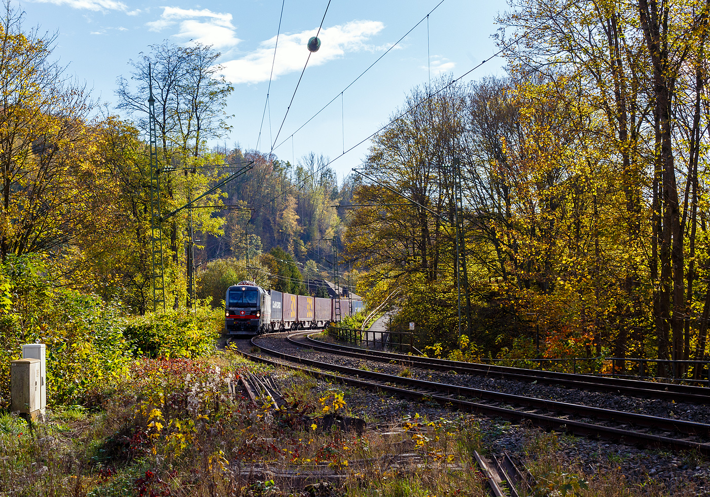 Ein fast fabrikneuer SIEMENS XLoad-Vectron, gerade mal 4 Wochen alt.
Die an die SBB Cargo International AG vermietete 193 549 mit XLoad  Duomo Milano  (91 80 6193 549-3 D-SIEAG) der SüdLeasing GmbH, Stuttgart (eingestellt in Deutschland durch Siemens) fährt am 29.10.2024 mit einem KLV-Zug, durch Kirchen (Sieg) in Richtung Siegen.

Die Multisystemlokomotive Siemens Vectron MS wurde 2024 von Siemens Mobilitiy in München-Allach unter der Fabriknummer 23595 gebaut und am 25.09.2024 ausgeliefert. Sie wurde in der Variante A40-1a ausgeführt und hat so die Zulassung für Deutschland, Österreich, die Schweiz, Italien, die Niederlande und Belgien (D / A / CH / I / NL / B). Sie verfügt über eine Leistung von 6,4 MW (160 km/h) und ist neben den nationalen Zugsicherungssystemen mit dem Europäischen Zugsicherungssystem (ETCS  BL3) ausgestattet. Zudem ist sie mit der neuen Ausrüstungspaket XLoad ausgestattet. 

Das neue XLoad Ausrüstungspaket für Vectron:
XLoad ist ein Ausrüstungspaket für Vectron, welches künftig mitbestellt, aber auch bei bereits ausgelieferten Vectron Loks nachgerüstet werden kann. Das Feature verbessert die Reibwertausnutzung und ermöglicht dadurch höhere Anhängelasten. Zudem reduzieren die Fahreigenschaften, die das Feature bewirken, den Verschleiß von Rad und Schiene.

Aktuell sind die Schweizer Vectron-Lokomotiven (SBB Cargo und BLS Cargo) in der Regel in Doppeltraktion unterwegs. Die Steigungen und Rampen der Schweizer Berge sind vor allem bei schlechten Witterungsbedingungen nicht ohne. Eine Lokomotive muss auch bei geringerem Schlupf genügend Traktion auf die Schienen bringen, um alle Güter sicher und zuverlässig ans Ziel zu bringen. Ein effizienter Weg aus dieser «Misere» ist die für Vectron entwickelte Zusatz-Funktion «XLoad». Den erfolgreichen Beweis trat eine SIEMENS Testlokomotive im Frühjahr 2022 bei der SBB Cargo International und bei der BLS Cargo eindrücklich an. 

Für SBB Cargo International bewies die Test-Lokomotive am Bözberg und für BLS Cargo an der Nordrampe des Lötschbergs ihre enorme Zugkraft. 
Vectron meisterte im Frühjahr 2022 die lange 12‰-Steigung des Bözbergs mit einer Anhängerlast von 2.000 Tonnen bravourös. Bei den nächtlichen Testfahrten zeigte sich eindrücklich die enorme Zugkraft der Lokomotive. 

Am Lötschberg wurden bei der BLS Cargo steigungsmäßig noch ein paar Promille draufgepackt. Mit 1.020 Tonnen im Gepäck bewältigte die Vectron-Lokomotive mit XLoad-Feature die 27‰-Steigung der Nordrampe ebenfalls meisterlich. Und auch diverse Anfahrtsversuche absolvierte der mit dem XLoad-Feature aufgerüstete Vectron problemlos. 

So bestellte die SüdLeasing GmbH (Stuttgart) im Auftrag der SBB Cargo International jüngst 20 Vectron Lokomotiven mit XLoad bei SIEMENS.
