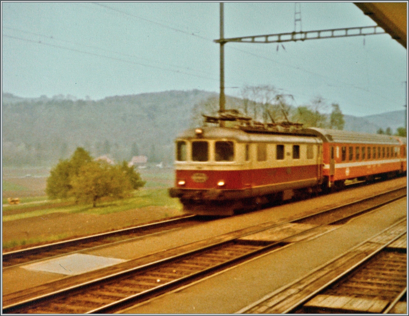 Eine SBB Re 4/4 I ist mit einem Schnellzug von Bern nach Paris auf dem Weg nach Pontarlier und fährt durch den Bahnhof von Gümmenen. 

Analogbild vom 3. Mai 1981