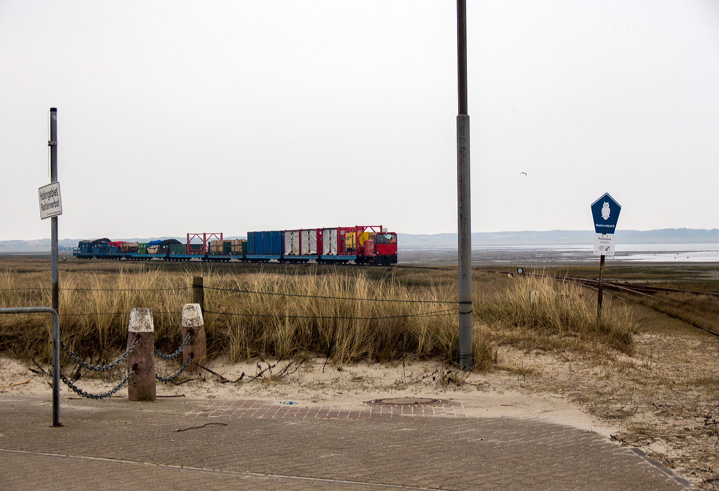 Es gibt in Deutschland auch noch schmalspurige Güterzüge, auch wenn die Wangerooger Inselbahn eine der letzten Schmalspurbahnen Deutschlands mit Güterverkehr ist. Zudem ist sie die letzte Schmalspurbahn der DB AG.

Hier kommt die DB 399 106-4 (98 80 3399 106-4 D-DB) der Wangerooger Inselbahn (SIW - Schifffahrt und Inselbahn Wangerooge),  eine ex VEB Mansfeld-Kombinat Wilhelm Piek - August-Bebel-Hütte vom Typ Faur L18H (Baujahr1990), kommt am 12 März 2024 mit einem Güterzug von Wangerooge durch die Salzwiesen und erreicht bald Wangerooge Westanleger. 

Am Westanleger wird der Güterzug dann mittels (20 t) Schwerlastgabelstapler entladen und kurz zwischen gelagert. Nach der Ankunft eines der (Cargo-) Versorgungsschiffe (RoRo-Schiffe), der Harle Express oder Harle Gatt, werden die Güter vom Schiff auf den nun leeren Güterzug umgeladen. Danach werden die zwischengelagerten Güter (meist auf oder in 20-Fuß Containern) mittels Schwerlastgabelstapler aufs Schiff verladen, die dann zum Festland nach Harlesiel gebracht werden. Da der Fähr- und Güterverkehr zwischen Harlesiel und der Insel Wangerooge sehr Tideabhängig ist, kann man oft Personen- und Güterverkehr gleichzeitig beobachten. 

Da der Fährhafen nicht, wie auf benachbarten Inseln, nahe an das Inseldorf verlegt werden kann, ist und bleibt die Wangerooger Inselbahn, auch aufgrund fehlender Alternativen, das Hauptverkehrsmittel der Insel.
