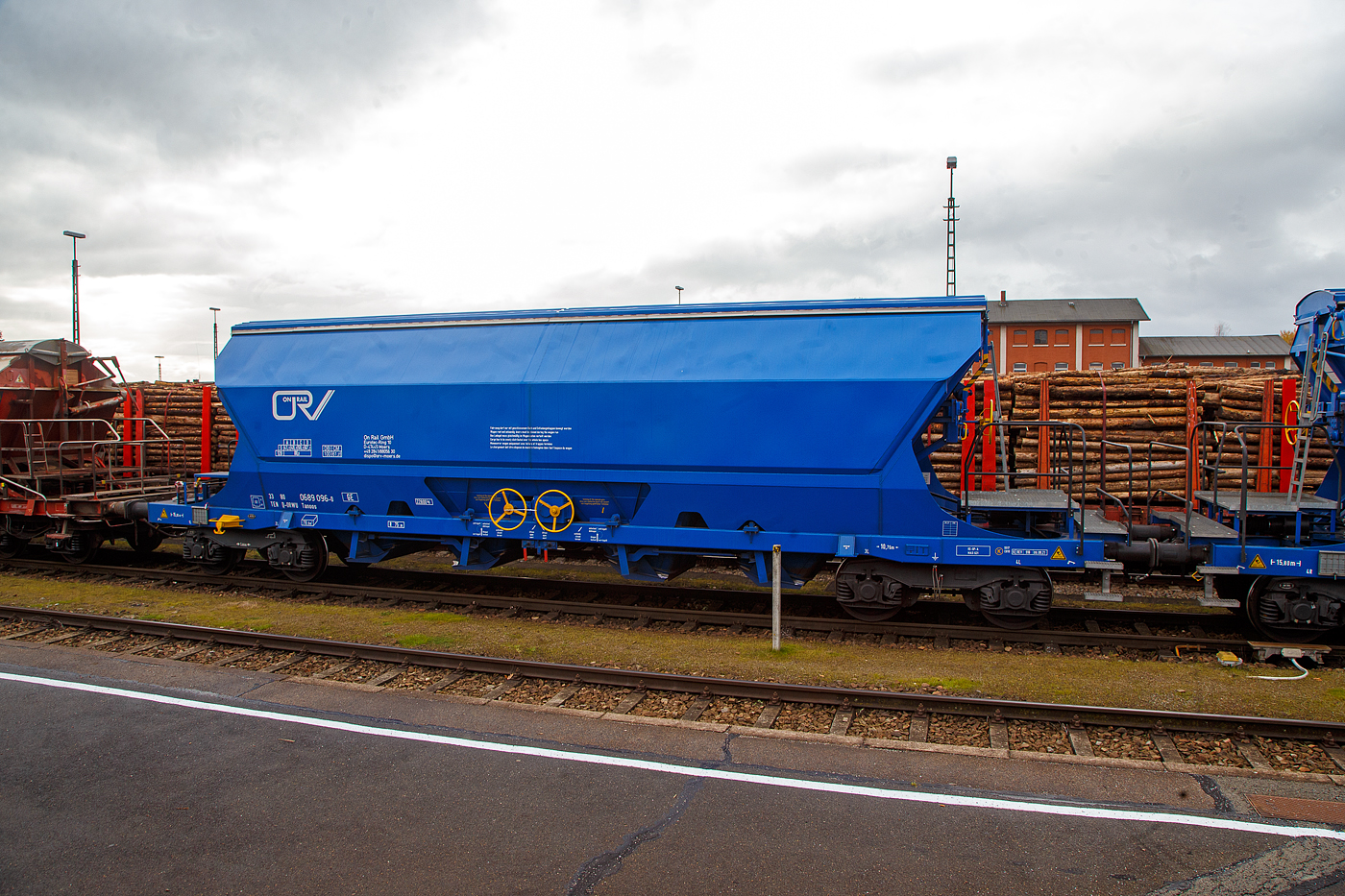 Gedeckter vierachsiger Drehgestell-78m³-Schüttgutwagen mit Schwenkdach und schlagartiger mittigen Schwerkraftentladung (Mittenselbstentladewagen) 33 80 0689 096-0 D-ORWU, der Gattung Tanoos, der Waggonvermietungsfirma On Rail GmbH (Mettman), abgestellt am 24.11.2022 im Bahnhof Schwandorf.

Der Wagen ist für den Transport von nässeempfindlichen Schüttgütern insbesonders korrosiv wirkenden, wie Kali sowie andere Düngemittel und Salze in granulierter Form, geeignet. Aus diesem Grund sind besonders gefährdete Bauteile und Berührungsstellen aus korrosionsfestem Stahl gefertigt. Der Wagenkasten besteht aus einem trichterförmigen Behälter, ist durchgängig und nur zwischen den Auslauföffnungen unterteilt. Die Entladung erfolgt über pyramidenförmige Auslauftrichter, die vier mittig angeordneten Entladeschieber werden paarweise über je ein Handrad betätigt. Alle Ecken und Aussteifungen sind durch Ausrundungen so gestaltet, dass sich nahezu keine Ladegutreste festsetzen können. Schräggestellte Behälterwände haben eine Neigung von 55° bzw. 60° zur Horizontalen. Der Wagenkasten ist so gestaltet, dass er von außen maschinell gereinigt werden kann. Die zweischalige Konzeption des manuell bedienbaren Dachs ist mit einer Kippeinrichtung versehen, die eine optimale Innenreinigung ermöglicht.

TECHNISCHE DATEN:
Hersteller: ELH Waggonbau Niesky GmbH
Spurweite: 1.435 mm
Länge über Puffer : 15.800 mm
Drehzapfenabstand: 10.760 mm
Achsabstand im Drehgestell: 1.800 mm
Laufraddurchmesser: 920 mm (neu)
Eigengewicht: 22.800 kg
Höchstgeschwindigkeit:  100  km/h (beladen) / 120 km/h (leer)
Maximales Ladegewicht: 67,2 t (Streckenklasse D oder höher)
Nat. max. Ladegewicht auch: 61, 2 t (DB Streckenklasse CM - 21 t Radsatzlast)
Kleinster bef. Gleisbogenradius: 75 m
Rauminhalt: 78 m³
Bremse: KE-GP-A (K)
Bremssohle: S517 / C 810
Intern. Verwendungsfähigkeit: TEN-GE

Die Bedeutung der Gattungs- und Kennbuchstaben (hier Tanoos):
T - Wagen mit öffnungsfähigem Dach 
a - mit vier Radsätzen
n - mit vier Radsätzen höchste Lastgrenze über 60 t
oo - mit Schwerkraftentladung, schlagartig, mittig, tiefliegend
s - Höchstgeschwindigkeit 100 km/h (beladen)
