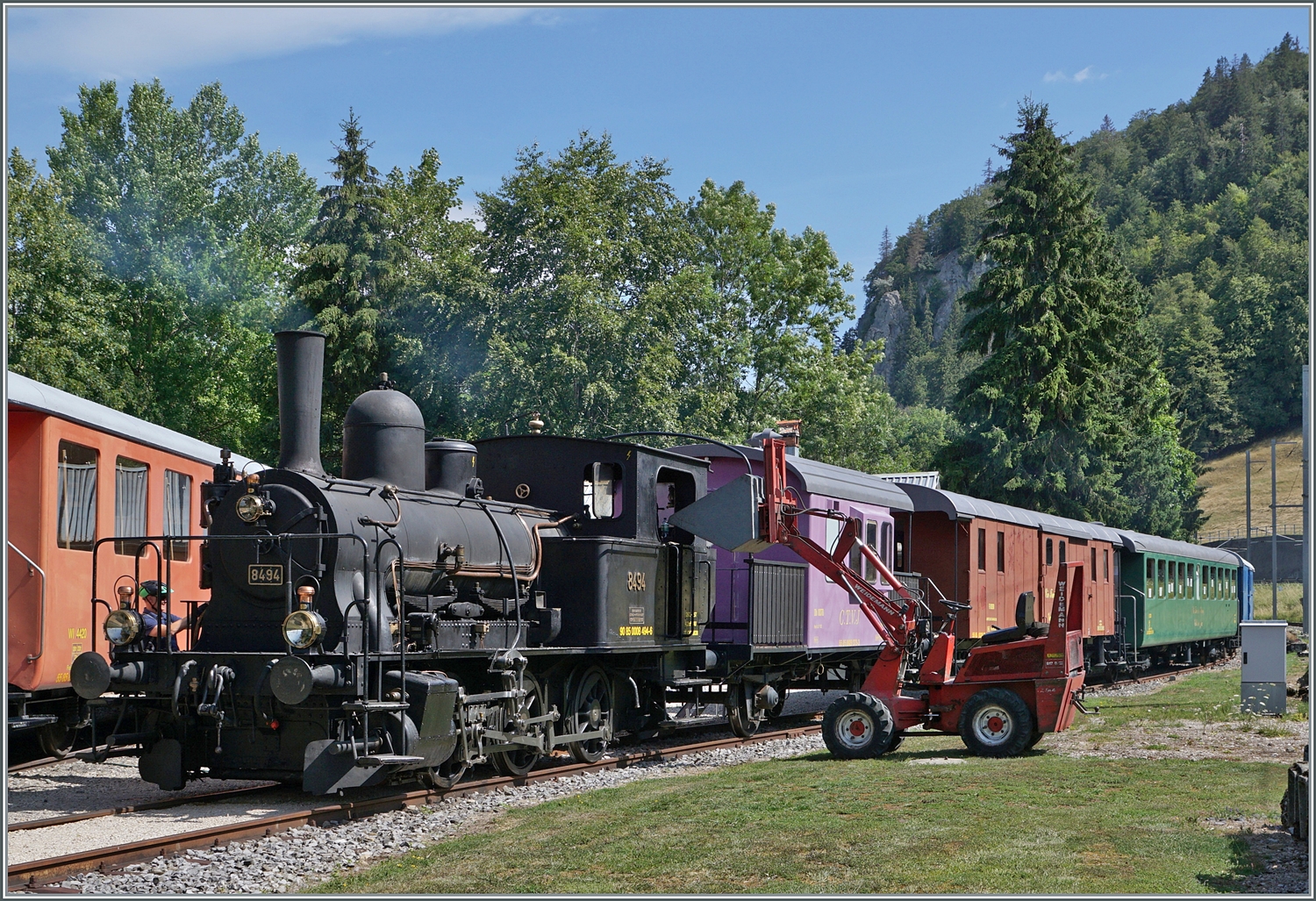 Gut 30 Km weiter ist ein weiteres  Tigerli  am dampfen! Die CTVJ (Compagnie du Train a vapeur de la Vallée de Joux) E 3/3 8494 (UIC 90 85 0008 494-6) mit der SLM Fabriknummer 1974 mit dem Baujahr von 1909 wird im Gelände der CTVJ in Le Pont für den nachmittäglichen Sonderzug nach Le Brassus vorbereitet. Auch hier wird die Lok mit Holz beheizt, welches aus dem (leicht das Bild störenden) Fahrzeug recht des Lok Stück um Stück entnommen wird. 

23. Juli 2023