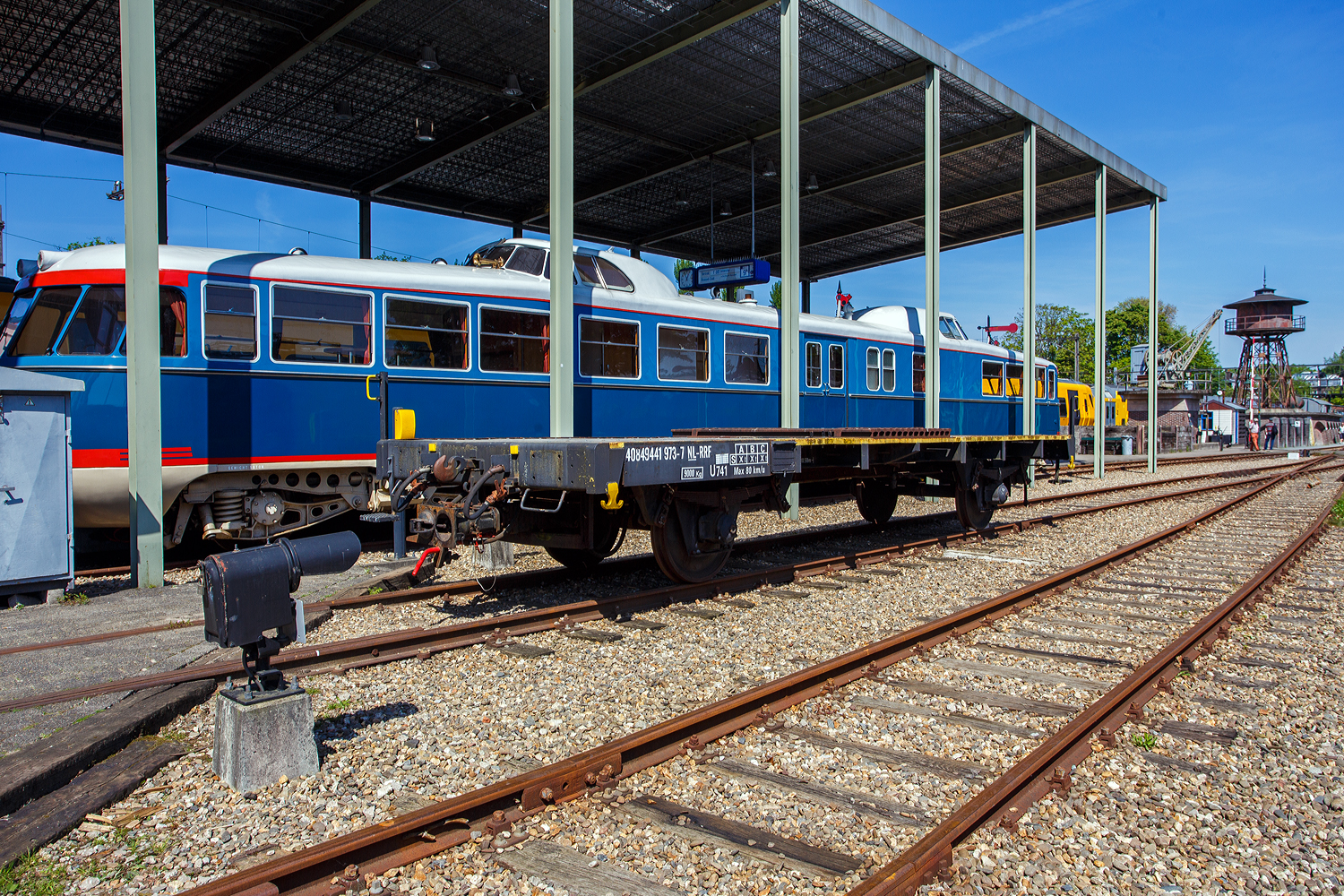 Hier ein weiterer zweiachsiger Kupplungswagen (Koppelwagen) ex 40 84 9441 973-7 NL-RFF (Rotterdam Rail Feeding), ex NS 01 84 1272 371-2, ex NS 7792, der Gattung U741, am 29 April 2025 im Het Spoorwegmuseum (bis 2005 NSM - Nederlands Spoorwegmuseum / Niederl�ndischen Eisenbahnmuseum) in Utrecht im ehemaligen Bahnhof Maliebaan. Dahinter steht “De Kameel“ (das Kamel) NS 20 (DE1 – 20). 

Diese Adapter- oder Kupplungswagen sind n�tig, wenn man mit einer Lok mit Puffern und Schraubkupplung Triebwagen und -z�ge mit Scharfenberger-Kupplung rangieren oder abschleppen muss. 

Nach dem Umbau (ca. 1960) aus Flachwagen erhielt der Wagen an erst an beiden Wagenenden eine Scharfenberger-Kupplung. Auf der Ladefl�che 
des Fahrgestells wurden au�erdem quer 15 Stahlschienen f�r zus�tzlichen Ballast angebracht. An zwei Ecken wurden Rangiertritte angebracht. 

Die Kupplungsh�he betr�gt fest 610 mm �ber Schienenoberkante und ist nicht wie bei anderen h�henverstellbar, somit k�nnen nur Triebz�ge der Typen mat'46, mat'54, DE 1, DE 2 und DE 3 gekuppelt werden. Aufgrund fehlender Luftanschl�sse an der Scharfenberger-Kupplung ist diese Kupplung ausschlie�lich mechanisch. Aber z.B. die Rangierloks der Serien 100, 200 und 300 (Orsik und Sik) haben eh keine Druckluftbremse. Der Wagen war beim Wph Amersfoort stationiert.

Sp�ter wurde die Scharfenberger-Kupplung an einem Wagenende wieder entfernt und erhielt dort wieder Puffern und Schraubkupplung.

2004 ging der Wagen �ber die RFF an das Eisenbahnmuseum, wo er heute ausschlie�lich auf der Utrechter Maliebaan eingesetzt wird.

TECHNISCHE DATEN:
Spurweite: 1.435 mm (Normalspur)
Anzahl der Achsen: 2
L�nge �ber Puffer: 10.580 mm
Achsabstand: 6.000 mm
Ladefl�che: 
Leergewicht: 9.000 kg
Max. Zuladung: 0 kg (Nur als Kupplungswagen verwendbar)
H�chstgeschwindigkeit: 80 km/h
