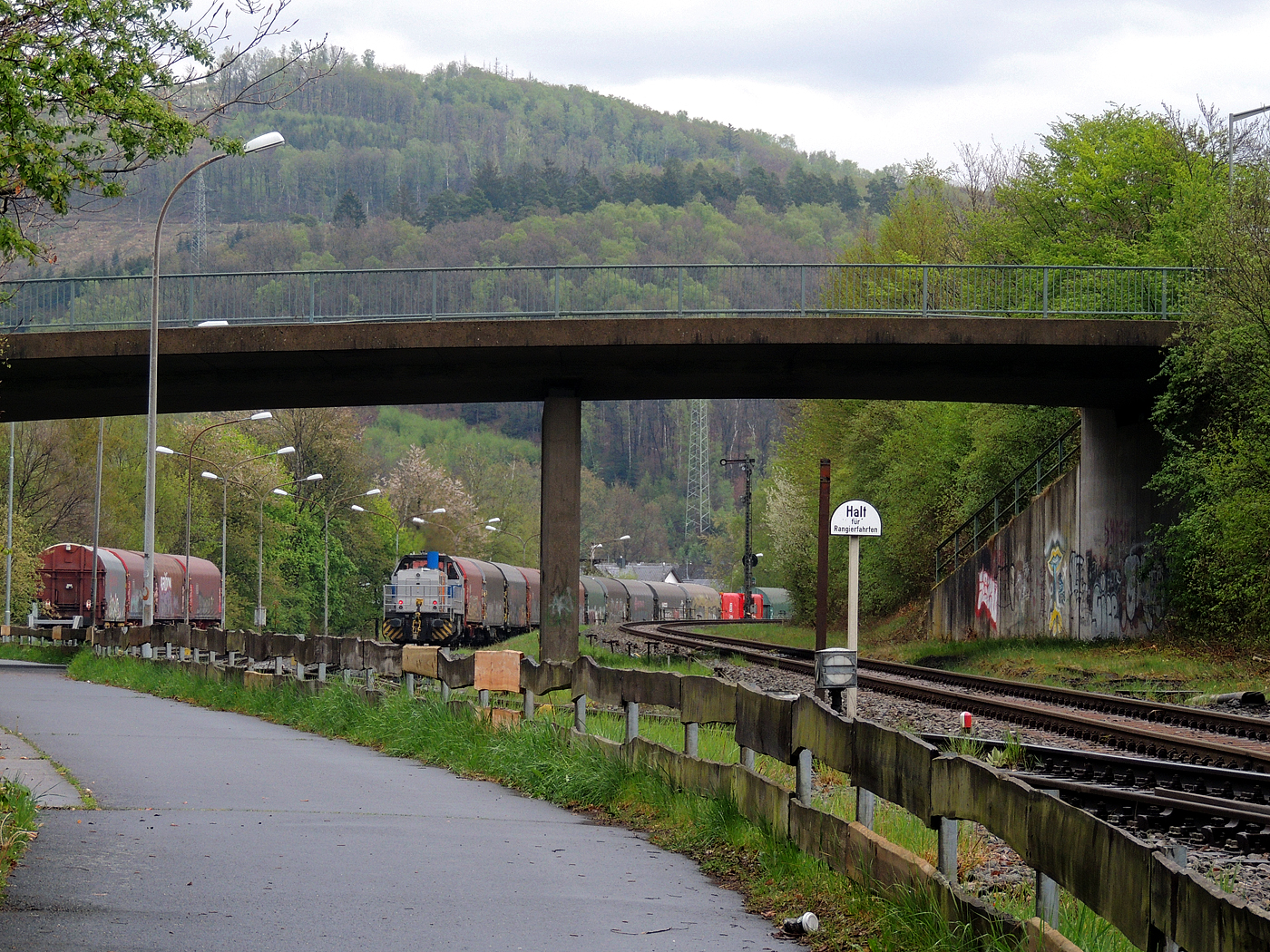 Hochbetrieb in Herdorf am 23 April 2025: 
Durch die vergangenen Osterfeiertage braucht es wohl wieder Nachschub. Die KSW (Kreisbahn Siegen-Wittgenstein) kommt im Sandwich mit einem sehr langen und somit schweren Coilzug, von via Betzdorf/Sieg kommend, und erreicht den KSW-Rangierbahnhof (Betriebsstätte FGE - Freien Grunder Eisenbahn).

Hier am Zugschluss die nachschiebende KSW 47 (92 80 1271 027-5 D-KSW), ex D 2 der HFM, eine Vossloh G 1000 BB, vorne als Zuglok die KSW 44 (92 80 1271 004-4 D-KSW) auch eine MaK G 1000 BB. Im Rbf wird der Zug geteilt, da er für die Weiterfahrt sonst zu lang wäre, und die KSW 44 zieht den ersten Teil weiter zu den Schäfer Werke KG am Pfannenberg in Neunkirchen-Salchendorf. 

Die KSW-Bahnstrecke Herdorf–Pfannenberg-(ehem. Unterwilden) ist eine rund 8 km lange Nebenbahn, bekannt ist sie auch als „Talbahn“. Die Strecke wurde von der 1904 gegründeten Freien Grunder Eisenbahn AG betrieben. Die gebliebenen Gleise und Anlagen sind seit 1970, als Betriebsstätte FGE - Freien Grunder Eisenbahn. Teil der heutigen Kreisbahn Siegen-Wittgenstein.

Später kam dann noch die KSW 43 (92 80 1273 018-2 D-KSW), die asymmetrische Vossloh G 2000 BB, mit einem langen Coilzug von Duisburg an.