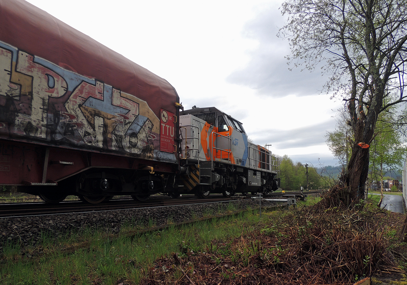 Hochbetrieb in Herdorf am 23 April 2025: 
Durch die vergangenen Osterfeiertage braucht es wohl wieder Nachschub. Die KSW (Kreisbahn Siegen-Wittgenstein) kommt im Sandwich mit einem sehr langen und somit schweren Coilzug, von via Betzdorf/Sieg kommend, und erreicht den KSW-Rangierbahnhof (Betriebsstätte FGE - Freien Grunder Eisenbahn).

Hier am Zugschluss die nachschiebende KSW 47 (92 80 1271 027-5 D-KSW), ex D 2 der HFM, eine Vossloh G 1000 BB, vorne als Zuglok die KSW 44 (92 80 1271 004-4 D-KSW) auch eine MaK G 1000 BB. Im Rbf wird der Zug geteilt, da er für die Weiterfahrt sonst zu lang wäre, und die KSW 44 zieht den ersten Teil weiter zu den Schäfer Werke KG am Pfannenberg in Neunkirchen-Salchendorf. 

Die KSW-Bahnstrecke Herdorf–Pfannenberg-(ehem. Unterwilden) ist eine rund 8 km lange Nebenbahn, bekannt ist sie auch als „Talbahn“. Die Strecke wurde von der 1904 gegründeten Freien Grunder Eisenbahn AG betrieben. Die gebliebenen Gleise und Anlagen sind seit 1970, als Betriebsstätte FGE - Freien Grunder Eisenbahn. Teil der heutigen Kreisbahn Siegen-Wittgenstein.

Später kam dann noch die KSW 43 (92 80 1273 018-2 D-KSW), die asymmetrische Vossloh G 2000 BB, mit einem langen Coilzug von Duisburg an.