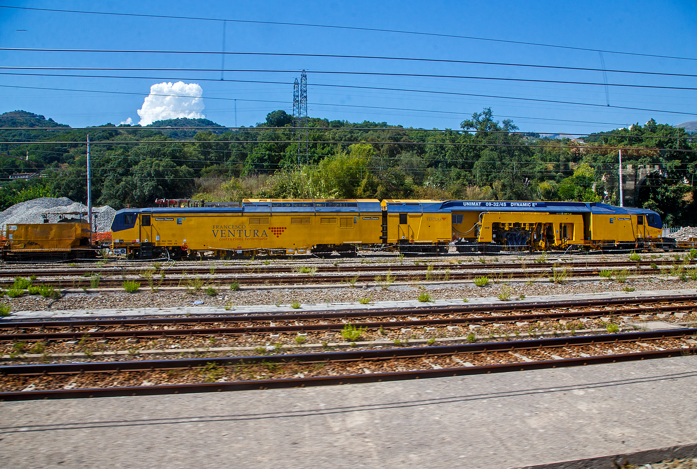 In Italien laufen schon die hochmodernen Maschinen mit Hybrid-Antriebssystem E�...
Hier ist die Plasser & Theurer UNIMAT 09-32/4S Dynamic E� der Francesco Ventura Costruzioni Ferroviarie S.r.l. (Paola/Italien), geh�rt zur Salcef Group, am 16.07.2022 beim Bahnhof Sapri (Kampanien) abgestellt. Aufnahme aus einem IC heraus.

Das Plasser & Theurer Hybrid-Antriebssystem E� treibt eine gro�e, kontinuierlich arbeitende Weichenstopfmaschine an. Das neue Hybrid-Antriebskonzept E� treibt die Maschine entweder durch einen Diesel- oder durch einen Elektromotor an, und zwar durch Nutzung der elektrischen Energie aus dem Fahrdraht (eine Nutzung durch Akkupower ist auch m�glich). Beide Motoren erzeugen den Hydraulikdruck f�r alle Systeme, vom Fahrantrieb f�r �berstell- und Arbeitsfahrt bis zu den Arbeitsaggregaten. 

E�-Maschinen von Plasser & Theurer stehen f�r: Economic – Ecologic – Ergonomic.
