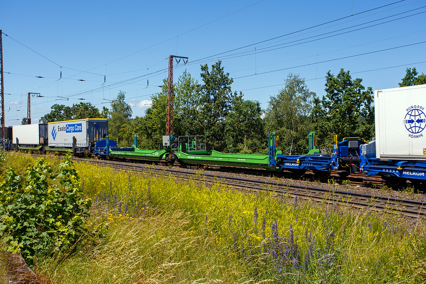 Leerer spezieller sechsachsiger Gelenk-Taschenwagen System HELROM, 33 80 4878 013-4 D-HELR, der Gattung Sdmrs, der HELROM Trailer Rail am 28 Juni 2024 im Zugverband bei der Durchfahrt in Rudersdorf (Kreis Siegen).

Der Clou bei HELROM sind neuartige Transportwaggons, die keine teuren Kran- oder Verladeeinrichtungen brauchen. Dieses Megaswing-System ist ein spezieller Taschenwagen mit schwenkbaren Aufnahmewannen für Sattelauflieger. Hydraulikstützen dienen als Stabilisierung, wenn die Wanne nach links oder rechts ausschwenkt. Die Beladung der Wanne mit einem Sattelauflieger erfolgt rückwärts. Nach Absatteln des Sattelaufliegers wird die Wanne angehoben und schwenkt wieder ein. Der Sattelauflieger wird leicht abgesenkt und mit dem Waggon fest verbunden, er ist nun auf dem Waggon sicher verstaut. Die Technik ist im Waggon verbaut.

TECHNISCHE DATEN:
Hersteller: Gök Yapi  (Türkei)
Spurweite: 1.435 mm
Länge über Puffer: 34.230 mm
Drehzapfenabstand: 2 x 14.200 mm
Achsabstand im Drehgestellen: 1.800 mm
Laufraddurchmesser: 920 mm (neu)
Eigengewicht: 45.700 kg 
Max. Zuladung bei Lastgrenze: 76,0 t (ab Streckenklasse D)
Max. Geschwindigkeit: 100 km/h (beladen) / 120 km/h (leer)
Kleinster befahrbarer Gleisbogen: R 75 m
Bremse: 2 x MH-GP-A (K)
Bremssohle: Cosid 810
Feststellbremse: Ja (auf ein Drehgestell)
Intern. Verwendungsfähigkeit: TEN-GE