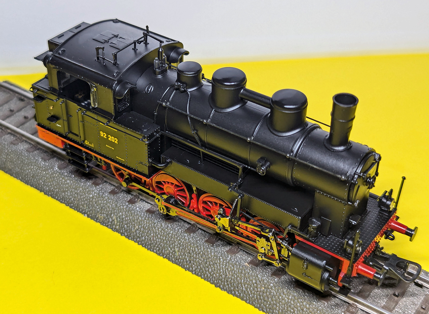 Mein HO Modell von Liliput (L131352 H0 AC) der badischen Dampflok  DR 92 202 (Epoche II – 1925 bis 1945), eine schöne und detaillierte Nachbildung einer Badische X b, hier am 19.10.2024 in Herdorf.

ORIGINAL:
Das Original wurde 1907 von der Maschinenbau-Gesellschaft Karlsruhe unter der Fabriknummer 1727 und als Baden 218 an die BadStB - Großherzoglich Badische Staatseisenbahn geliefert. Ab 1925 wurde sie von der Deutschen Reichsbahn als DR 92 202 eingeordnet.

Ab 1907 beschaffte die Badische Staatsbahn für den schweren Rangierdienst diese vierachsigen Tenderlokomotiven der badischen Reihe X b, von denen bis 1921 insgesamt 98 Lokomotiven geliefert wurden. Die Lokomotiven konnten in der Ebene einen 720 t schweren Zug mit 45 km/h und einen 100-t-Zug bei 20 ‰ mit 35 km/h ziehen.

TECHNISCHE DATEN:
Spurweite: 1.435 mm (Normalspur)
Bauart : D n2t
Gattung: Gt 44.15
Länge über Puffer: 10.650 mm
Höhe: 4.500 mm
Gesamtachsstand: 4.350 mm
Dienstgewicht:  58,1 t
Achslast : 15,0 t
Höchstgeschwindigkeit: 45 km/h (vorwärts / rückwärts)         
Leistung: 500 PS
Treibraddurchmesser: 1.262 mm
Zylinderanzahl:  2
Zylinderdurchmesser: 480 mm
Kolbenhub: 630 mm
Kesselüberdruck: 13 bar
Kohlenvorrat: 2,5 Tonnen
Wasservorrat: 7 m³

Konstruktive Merkmale
Die Lokomotive verfügte über einen Blechrahmen aus durchlaufenden 21 mm dicken Platten. Versteifungen wurden durch Längs- und Querrippen erreicht. Ein zwischen den Rahmenwangen angeordneter T-förmiger Wasserkasten diente ebenfalls der Versteifung.

Der Crampton-Kessel bestand aus zwei Schüssen. Auf dem vorderen Schuss saßen zwei Dampfdome mit einem Verbindungsrohr. Dadurch wurde ein Überreißen des Wassers vermieden. Auch die Elastizität des Kessels bei unterschiedlichen Anhängelasten wurden damit verbessert. Auf dem hinteren Schuss saß der Sandkasten und das Pop-Sicherheitsventil. Durch die hohe Kessellage konnte der Stehkessel über dem Rahmen angeordnet werden. Die Feuerbüchse war aus Kupfer. Das außenliegende waagerecht angeordnete Zweizylinder-Nassdampftriebwerk arbeitete auf die dritte Kuppelachse. Die Kolbenstange wurde vorn und hinten geführt. Die außenliegende Heusinger-Steuerung besaß Hängeeisen. Die Umsteuerung erfolgte durch Handhebel.

Das Laufwerk war an vier Punkten abgestützt. Die Federn befanden sich unterhalb der Achslager. Die beiden Blattfederpakete der beiden vorderen und der beiden hinteren Radsätze waren mittels Ausgleichshebeln miteinander verbunden. Der zweite und vierte Radsatz waren 25 mm nach jeder Seite verschiebbar. Die Lokomotiven verfügten über eine Westinghouse-Druckluftbremse. Dazu besaßen die Maschinen eine Handhebelbremse. Die Bremsen wirkten auf alle Kuppelräder von vorn.

Die Brüggemann-Sandeinrichtung sandete den dritten Kuppelradsatz bei Vor- und Rückwärtsfahrt. Für den Einsatz im Hafen Mannheim wurden die Lokomotiven mit einem Funkenfänger versehen. Die Maschinen verfügten über eine Dampfheizungseinrichtung.
