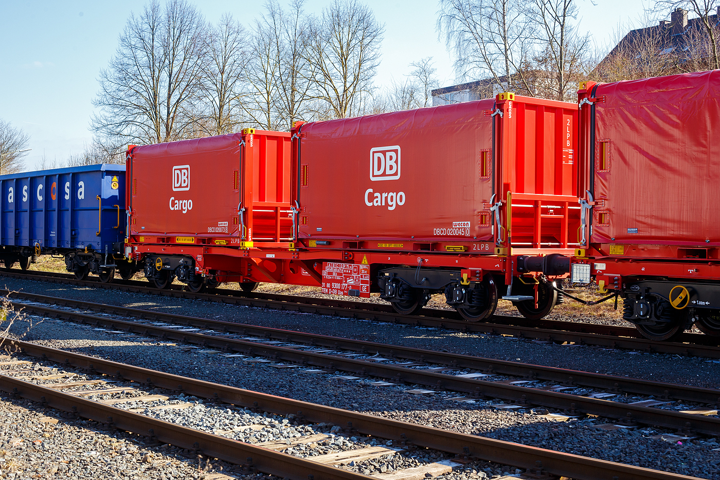 NEUHEIT - Die neusten Güterwagen DB Cargo AG
Neuer vierachsiger Drehgestell-Güterwagen 31 80 9300 177-0 D-DB der Gattung Uas 224.2 der DB Cargo AG am 17 Februar 2025 abgestellt, im Zugverband eines Übergabegüterzuges, in Herdorf auf dem KSW Rbf Herdorf (Betriebsstätte Freien Grunder Eisenbahn - NE 447). Der Wagen (m² Wagen 45ft) ist hier beladen mit zwei Coil-Behältern (20-Fuß-Container), welche bis zu 3 Blech-Coils mit einem Gesamtgewicht bis zu 30 t aufnehmen kann.

TECHNISCHE DATEN Wagen (laut Anschriften):
Gattung: Uas 224.2
Spurweite: 1.435 mm (Normalspur)
Länge über Puffer: 15.220 mm
Drehzapfenabstand: 9.680 mm
Radsatzstand in den Drehgestellen: 1.800 mm
Eigengewicht: 18.200 kg
Max. Zuladung: 71,8 t (ab Streckenklasse D)
Max. Geschwindigkeit: 100 km/h (beladen) / 120 km/h (leer)
Kleinster Gleisbogenhalbmesser: 75 m
Bauart der Bremse: KE-GP-A (K)
Bremssohle: Cosit 810
Handbremse: Ja (an einem Drehgestell)
Intern. Verwendungsfähigkeit: TEN-GE

Der multifunktionale und modulare Güterwagen m² ist eine neue und innovative Technologie für den Güterwagen der Zukunft. Das Konzept wurde in Zusammenarbeit von DB Cargo und VTG entwickelt.

Die heutigen Güterwagenflotten sind geprägt durch eine große Diversifizierung des Wagenparks, mit vielen unterschiedlichen Bauarten und mangelnder Flexibilität hinsichtlich des Einsatzes und der Verwendung. So werden Wagen für den Transport bestimmter Güter für einen Zeitraum von mehreren Jahrzehnten beschafft und es besteht im Lebenszyklus keine Möglichkeit, den Einsatzzweck zu verändern. Die ausgeprägte Spezialisierung der heutigen Güterwagenbeschaffung führt zu einem erhöhten Risiko von Fehlinvestitionen über den langen Lebenszyklus der Fahrzeuge.

Der m²-Güterwagen basiert auf einem Untergestell als variable Plattform mit veränderbarer Länge. Darauf können die verschiedensten Behälter zum Transport unterschiedlicher Güter montiert werden. Dieses innovative Konzept eines multifunktionalen und modularen Güterwagens ermöglicht eine flexible Nutzung durch Kombination aus wirtschaftlichem Baukastenprinzip (modular) und einer vielseitig einsetzbaren Verwendung (multifunktional).

Die Zulassung eines Güterwagens als komplettes und flexibles System ist ein echter Meilenstein. 

Merkmale:
▪ modularer Tragwagen zum Transport von kundenindividuellen Behältern
▪ Zulassung als Güterwagensystem seit 31.05.2021 vorliegend
▪ Anpassung wesentlicher Wageneigenschaften im Lebenszyklus ohne erneute Zulassung möglich
▪ Wagen ist an sich ändernde Marktanforderungen durch Modularität flexibel anpassbar
▪ Längen des Tragwagens im Lebenszyklus veränderbar
▪ Behälter sowie Aufbauten tauschbar und Kopplungsmöglichkeiten mit Wagen gegeben
▪ Uneingeschränkte EV-Fähigkeit des Tragwagens

Persönliche Anmerkung: Eine solcher mit 2 Coilbehälter ist um ca. 3 m länger als z.B. ein Coilwagen der Gattung Shimmns, aber dafür haben die Behälter, mit den Gabelstaplertaschen und den Containereckbeschlägen, vielfältige Umschlags- und Lagermöglichkeiten.

Die Coil-Behälter:
Hersteller: Wecon GmbH
Hersteller der Plane: Schleswiger Tauwerkfabrik Oellerking GmbH & Co. KG

Ausstattungsmerkmale sind:
− Leichtgängige Plane mit Antikondensatiosvlies
− Schnee- und Nässeschutz durch Gummilippe, Bürste und Regenrinne
− Ladungssicherung über Klaviatursicherung
− Planenfesttellbremse und Gitterroste zur Maximierung der Arbeitssicherheit
− Gabelstaplertaschen und Containereckbeschläge für vielfältige Umschlagsmöglichkeite

Dimensionen der Mulden:
Mulde 1 für Ø 780 bis 1.650 mm, mit max. 17 t
Mulde 2 für Ø 780 bis 2.100 mm, mit max. 30 t
Mulde 3 für Ø 780 bis 1.650 mm, mit max. 17 t
Die max. Ladebreite beträgt jeweils 2.240 mm, die max. Zuladung eines Containers beträgt mit 30 t. 

Containermaße (außen): 
Länge: 6.058 mm (20 ft.)
Breite: 2.438 mm
Höhe: 2.591 mm
Leergewicht: 4,5 t
Zuladung: 30 t
