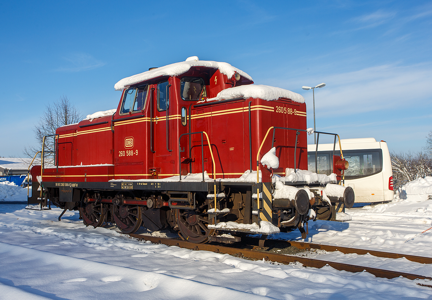Nicht nur im Süden der Republik hat es etwas geschneit, wie hier auf dem Westerwald auf der Bindweide, aber nicht so mächtig. 
Die 260 588-9 alias 360 588-8 (98 80 3360 588-8 D-BBFW) vom Bergische Bahnen Förderverein Wupperschiene e. V. ist am 03 Dezember 2023 (am 1. Advent) auf dem Betriebshof der Westerwaldbahn (WEBA) auf der Bindweide bei Steinebach/Sieg abgestellt.

Die V60 der leichten Ausführung wurde 1960 von Krupp unter der Fabriknummer 4011 gebaut und als V 60 588 an die Deutsche Bundesbahn geliefert. Nach der Umzeichnung 1968 in 260 588-9 und 1987 in 360 588-8 wurde die V60 im Jahr 2002 bei der DB ausgemustert und ging an die EfW-Verkehrsgesellschaft mbH in Frechen, bis sie 2013 zum Bergische Bahnen Förderverein Wupperschiene e. V. kam.

Die V60-Familie:
Die Deutsche Bundesbahn hatte nach ihrer Gründung einen Mangel an kleinen Rangierlokomotiven. Daher wurde ab 1951 eine Dieselrangierlok entwickelt, an deren Bau und Entwicklung fast alle namhaften Lokomotivfabriken beteiligt waren. Die neue Baureihe wurde zunächst als V 60 bezeichnet. Noch 1955 wurden die ersten 275 Serienloks in Auftrag gegeben, sie hatten den Motor GTO 6 von Maybach und das Dreiganggetriebe L 37 zUB von Voith.

Durch einen verstärkten Rahmen erhielten einige der Lokomotiven ein höheres Reibungsgewicht von 53 Tonnen (somit schwere Ausführung, spätere BR 261/361) statt 48,3–49,5 Tonnen. Zusätzlich konnten bei diesen Loks für den schweren Dienst noch bis zu sechs Tonnen Ballast mitgeführt werden, die Baureihenbezeichnung blieb jedoch bei V 60. Insgesamt wurden 942 Lokomotiven der leichten und schweren Ausführung zusammen genommen geliefert. Anhand der Ordnungsnummer war eine Unterscheidung der leichten und der schweren Ausführung nicht möglich, erst zum 1. Januar 1968 wurde mit der Einführung der computerlesbaren Nummern für die DB-Lokomotiven die Baureihe V 60 in die 618 Fahrzeuge umfassende Baureihe 260 (leichte Ausführung) und 322 Fahrzeuge umfassende Baureihe 261 (schwere Ausführung) aufgeteilt. Bei den vierstelligen Ordnungsnummern entfiel die führende Tausenderstelle.

Die V60 wurden 1987 als Kleinloks eingestuft und trug seitdem die Baureihenbezeichnung 360 (leichte Ausf.) bzw. 361 (schwere Ausf.). Die Einstufung als Kleinlok sparte Personalkosten, da die Bundesbahn nun keine „Lokführer“ mehr einsetzen musste, sondern „Kleinlokbediener“, deren Ausbildung günstiger war. Durch die Umstellung der Führerschein-Systematik hat die Einstufung als Kleinlok heute nur noch deklaratorische Bedeutung, die V 60 würde nach wie vor die technischen Anforderungen an „großen“ Lokomotiven gemäß EBO erfüllen. Der Einbau von Funkfernsteuerungen erlaubte Einmann-Rangierfahrten, die fernsteuerbaren Modelle wurden Baureihe 364 (leichte Bauart) bzw. 365 (schwere Bauart).
