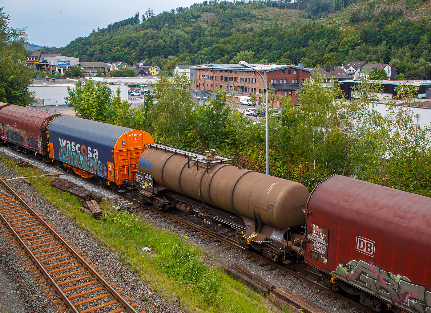 Nochmals von oben...
Der Vierachsiger-Drehgestell Kesselwagen für Salpetersäure (>97%), der Gattung Zacs, registriert als 33 80 7868 687-4 D-GATXD der GATX Rail Germany GmbH am 24.08.2023 in Herdorf, im Zugverband eines Übergabezuges der KSW.

Die Gefahrguttafel (885/2031) zeigt es auch noch an: (oben) Gefahrgutnummer 885 = stark ätzender Stoff / (unten) UN-Nummer 2031 = Salpetersäure, andere als rotrauchend, mit mehr als 70 % Säurebrandfördernd. Hier sogar (laut Anschrift) größer 97 %. Die reine Säure ist farblos und hat einen scharf stechenden Geruch. Sie wird unteranderem zur Herstellung von Sprengstoffen verwendet, was hier der Fall ist.

TECHNISCHE DATEN:
Gattung: Zacs
Spurweite: 1.435 mm
Länge über Puffer : 14.240 mm
Drehzapfenabstand: 9.200 mm
Achsabstand im Drehgestell: 1.800 mm
Höchstgeschwindigkeit: 100 km/h (120 km/h leer)
Eigengewicht: 20.985kg
Nutzlast: 59,0t ab Streckenklasse C
Gesamtvolumen: 44.900 Liter
Prüfdruck: 4 bar
Zulässiger Betriebsüberdruck: 3 bar
Tankcode: L10DH
Behälterwerkstoff : Edelstahl
Bremse: KG-GP
Intern. Verwendungsfähigkeit: RIV