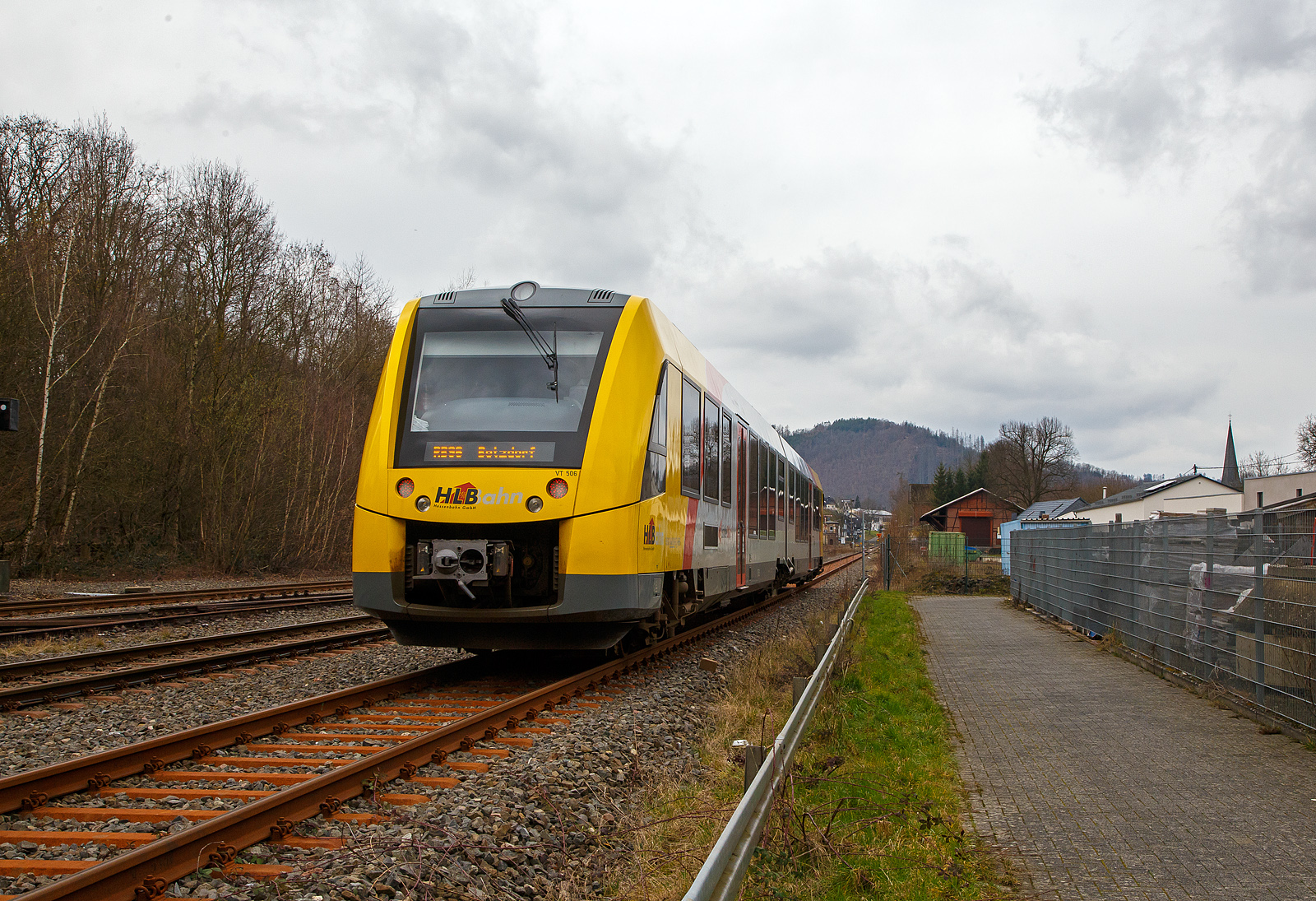 Nun fahren die Triebwagen der HLB RB 96 „Hellertalbahn“ auch endlich wieder den Bahnhof Herdorf an. Leider  ist aber dann in Herdorf am Hp Königstollen Schluss, ab dort gibt es dann von und nach Betzdorf (Sieg) SEV. Nach dem Hangrutsch (Felssturz) am 23. Dezember 2022 in Herdorf kurz hinter dem Hp  Königsstollen (bei km 88,4), ist der Abschnitt nach Betzdorf weiterhin bis mindestens bis zum kleinen Fahrplanwechsel am 11. Juni 2023, gesperrt. Aber diese ungewöhnliche Führung bis zum Hp  Königsstollen, über den Bahnhof Herdorf hinaus ist nötig, denn in den nächsten Tagen sollen die der Abriss und der Neubau der „Hellerbrücke“ der Hellerstraße (bei „Steinaus Eck“) beginnen und der SEV wäre so nur noch über Daaden oder Kirchen möglich.

Hier erreicht der VT 506 (95 80 1648 106-0 D-HEB / 95 80 1648 606-9 D-HEB), ein Alstom Coradia LINT 41 der neuen Generation / neue Kopfform, der HLB (Hessische Landesbahn GmbH) am 20.03.2023, als RB 96 „Hellertalbahn“ nach Betzdorf, bald den Bahnhof Herdorf.