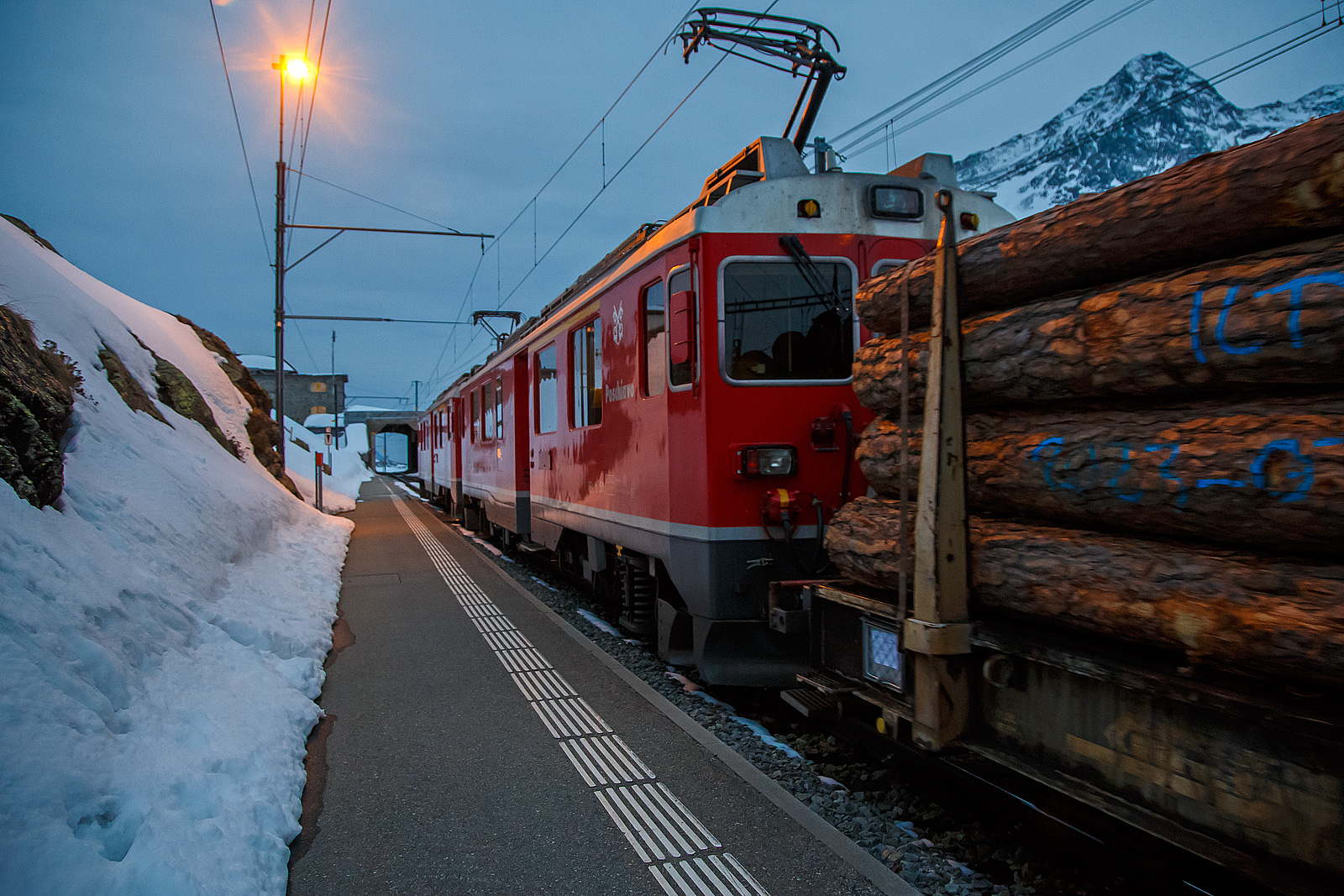 Nun haben die beiden RhB ABe 4/4 III Triebwagen 54  Hakone  und  51  Poschiavo  am 21.03.2023 als PmG (Personenzug mit G�terbef�rderung) nach Poschiavo, fahren nun vom h�chsten Punkt der Berninabahn, den Bahnhof Ospizio Bernina weiter nach Poschiavo.

Ab hier sind nun eher die Bremsen gefordert, denn nun geht es bis nach Poschiavo fast nur bergab. Von Pontresina nach Ospizio Bernina geht es nur bergauf, und wir merkten wie die Triebwagen arbeiten mussten.