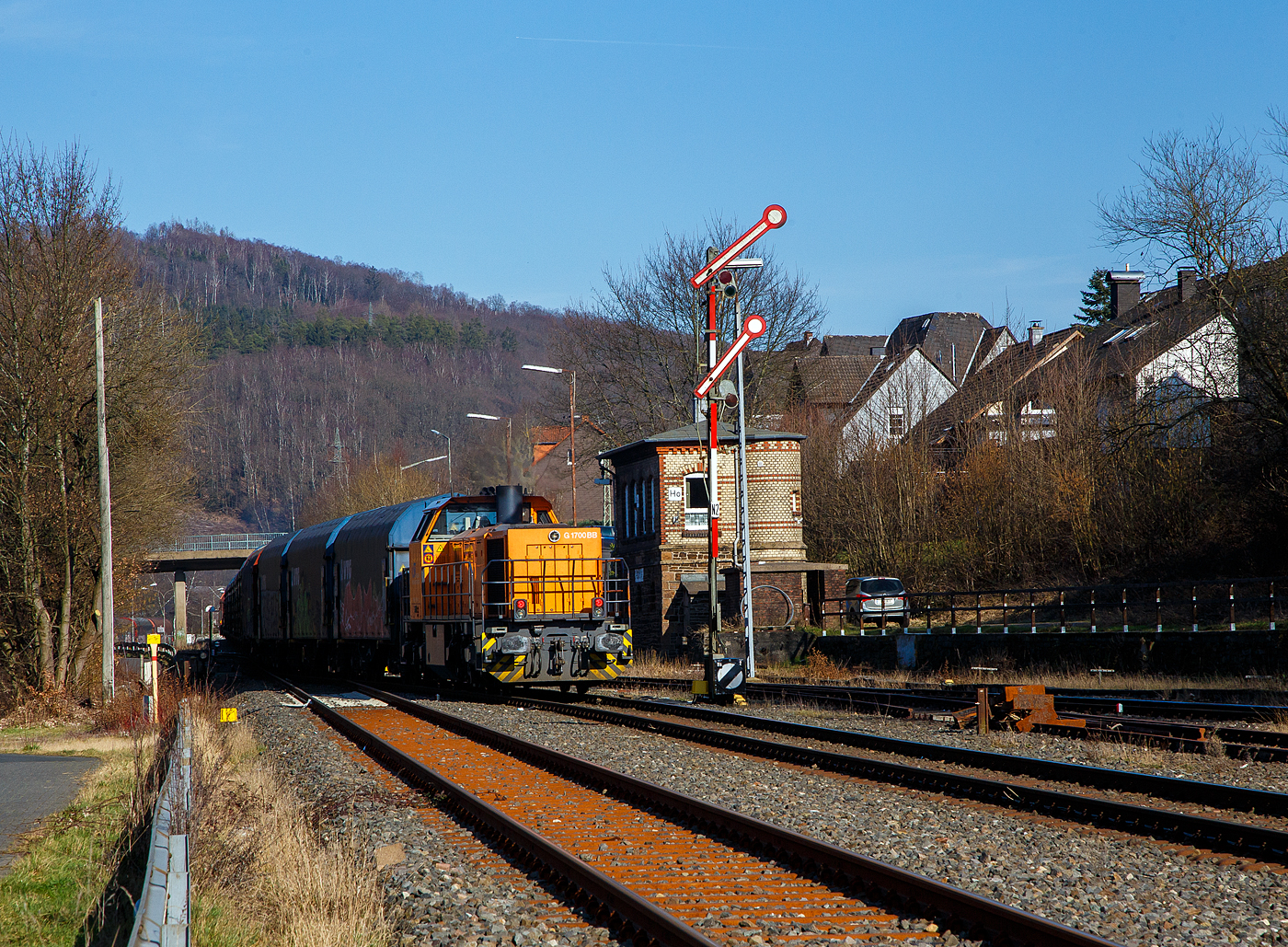 Nun hat der lange Übergabezug der KSW am 03.03.2023 im Bahnhof Herdorf Signal Hp 2 (Langsamfahrt) und die Fahrt nach Dillenburg kann beginnen. Es wird im Sandwich gefahren, vorne zieht die KSW 42 (92 80 1277 902-3 D-KSW), eine Vossloh MaK G 1700 BB und von hinten (hier im Bild) drückt die KSW 46 bzw. 277 807-4 (92 80 1277 807-4 D-KSW), eine Vossloh G 1700-2 BB.

Da dieser Zug eine beachtliche Länge hat, und die Gleislänge im KSW Rbf nicht ausreicht, muss im Bahnhof Herdorf gekuppelt werden. Eigentlich würde sie einfach via Betzdorf nach Kreuztal fahren, aber der Abschnitt Herdorf – Betzdorf bleibt, nach dem Felssturz am 23.12.2022 in Herdorf, bis voraussichtlich zum kleinen Fahrplanwechsel am 09. Juni 2023 gesperrt.