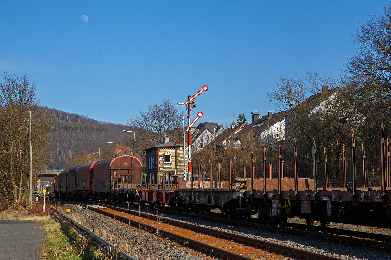 Nun hat der lange Übergabezug der KSW am 03.03.2023 im Bahnhof Herdorf Signal Hp 2 (Langsamfahrt) und die Fahrt nach Dillenburg beginnt. Es wird im Sandwich gefahren, vorne zieht die KSW 42 (92 80 1277 902-3 D-KSW), eine Vossloh MaK G 1700 BB und von hinten drückt die KSW 46 bzw. 277 807-4 (92 80 1277 807-4 D-KSW), eine Vossloh G 1700-2 BB. Übrigens ist Vollmond, den man hier auch gut sehen kann.

Da dieser Zug eine beachtliche Länge hat, und die Gleislänge im KSW Rbf nicht ausreicht, muss im Bahnhof Herdorf gekuppelt werden. Eigentlich würde sie einfach via Betzdorf nach Kreuztal fahren, aber der Abschnitt Herdorf – Betzdorf bleibt, nach dem Felssturz am 23.12.2022 in Herdorf, bis voraussichtlich zum kleinen Fahrplanwechsel am 09. Juni 2023 gesperrt.