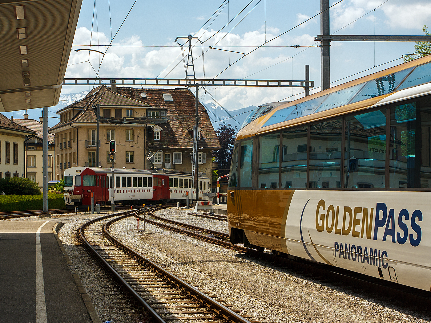 Nun verlässt der tpf - La Gruyère Meterspurtriebwagen BDe 4/4 – 142 „Semsales“ mit dem Steuerwagen Bt 252 am 28.05.2012 den Bahnhof Bulle in Richtung Broc. 

Den Bahnhof Bulle FR gibt es so nicht mehr, er wurde um 300 Meter in Richtung Norden gezogen. Vor 2019 befand sich der Bahnhof am südlichen Ende des Place de la Gare. Die normalspurige Eisenbahnstrecke Bulle–Romont endete am Bahnhof, während zwischen den Strecken Bulle–Broc und Palézieux–Bulle–Montbovon mit einer Spurweite von 1.000 mm ein Umstieg möglich war. Ein großes Renovierungsprojekt baute etwas nördlich an der Rue Rieter einen neuen Bahnhof. Im Rahmen dieses Projekts wurde die kurze 5,4 Kilometer lange Stichstrecke von Bulle nach Broc ist auf Normalspur umgebaut. 


Hauptargument für die Umspurung war der aufwendige Güterverkehr zur Cailler-Schokoladenfabrik mittels Rollböcken, welcher allerdings 2018 durch Nestlé auf die Straße verlagert wurde.Der Weiterbestand der Strecke war wegen ihres tiefen Kostendeckungsgrads gefährdet. Nach der Umspurung wird sie halbstündlich von den RegioExpress (RE) Freiburg–Bulle bedient, die bisher im Bahnhof Bulle eine Standzeit von 40 Minuten hatten. Damit kann eine Schmalspurkomposition eingespart werden.

Am 11. Dezember 2022 wurde der neue Bahnhof von Bulle vollständig in Betrieb genommen. Der Bahnhof, der Platz „Place de la Gare“, die Perrons, die Unterführung und die Informationseinrichtungen für die Reisenden sind eröffnet.
