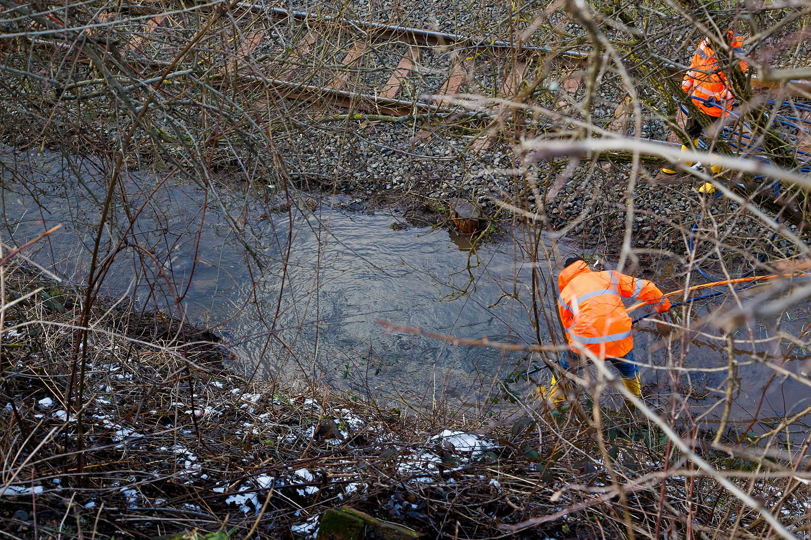 Schlimmer geht immer.....
Totalsperrung der Hellertalbahn (KBS 462 / Strecke 2651)
Nun ist Herdorf Bahntechnisch zur Insel geworden. 
Es gibt seit dem 10.03.23 eine Gleisunterspülung auf der Strecke 2651 bei km 91,0, so ist vorerst auch kein Güterverkehr von Haiger nach Herdorf möglich. Da die Strecke Betzdorf – Herdorf, bereits wegen dem Felsstutz  am 23.12.2022, seitdem gesperrt ist Herdorf nun Bahntechnisch ganz abgeschnitten. 

Eigentlich hatte ich am Mittag (11.03.2023) gedacht das Wasser fließt nun einfach ab. Aber leider war es am Nachmittag noch nicht so, der Wasserstand ist leider nur etwas gesunken. Zwei Arbeiter versuchen das Rohr zwischen dem einen Verteiler (ca. 50 m auseinander) zum anderen frei zubekommen. Links von dem Arbeiter der im Wasser steht, kommt von unten aus einem Rohr oder Stollen aber mächtig viel Wasser gequollen und fließt nach links in Richtung Herdorf bis zum Funkmast. Und sucht sich dann den Weg unter dem Gleisbett hindurch auf die andere Seite.