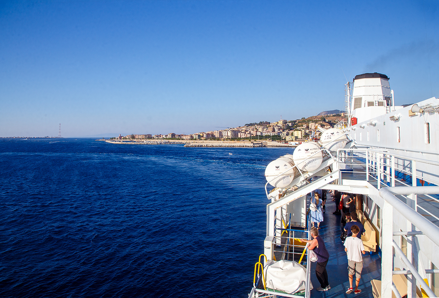 Sch�ner kann doch eine Bahnfahrt nicht mehr sein....
Nun sind wir und auch der Zug, am 16.07.2022, auf der Eisenbahnf�hre „SCILLA“ der RFI Rete Ferroviaria Italiana (zur Gruppe der Ferrovie dello Stato Italiane), und fahren mit ihr �ber die Stra�e von Messina nach Sizilien (Sicilia). Die F�hre wurde 1985 in Dienst gestellt und seitdem auf der Strecke von Villa San Giovanni nach Messina im Einsatz ist. Die Seefahrt/�berfahrt ist im Bahnticket eingeschlossen, geh�rt ja auch zur Eisenbahnstrecke. Wir hatten die Fahrt von Napoli Centrale nach Catania f�r 16,90 �/Pers. gebucht.
