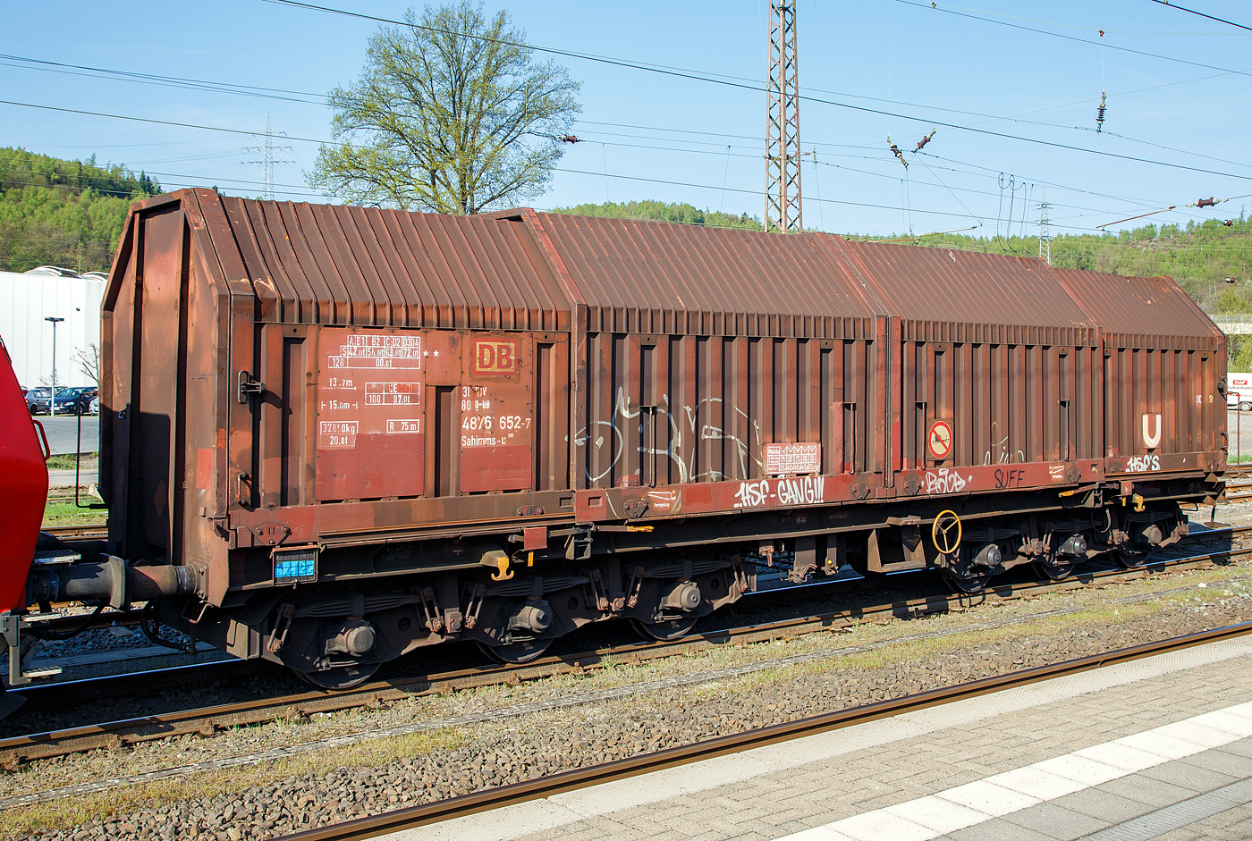 Sechsachsiger Drehgestellflachwagen für Coiltransporte mit verschiebbaren Teleskophauben und Lademulden für Coiltransporte, 31 80 4876 652-7 D-DB der Gattung Sahimms-u 900, der DB Cargo AG, am 20.04.2018  in Kreuztal.

LHB und Talbot entwickeln einen 6-achsigen Haubenwagen für den Transport schwerer Coils, von dem 1981 sechs Prototypen geliefert und bei der DB als Sahimms 900 bezeichnet werden. Dieser Wagen wurde 1984 von der Waggonfabrik Talbot in Aachengebaut.

Die Wagenabdeckung besteht aus vier verschiebbaren Stahl-Teleskophauben, die sich einseitig oder zu beiden Wagen enden hin soweit übereinander schieben lassen, dass jeweils 40% der gesamten Ladelänge freigelegt sind. Die Wagen besitzen insgesamt fünf feste Mulden, wobei die beiden äußeren Mulden Coils mit einem Gewicht von maximal 25 t und einem maximalen Durchmesser von 2.250 mm, die mittleren drei Mulden Coils mit maximal 45 t Gewicht bei einem maximalen Durchmesser von 2.700 mm aufnehmen können. 

Im Jahre 1984 erfolgt ein Serienbau von 300 Teleskophaubenwagen. 1986/87 baut Waggonbau Niesky eine Serie von 145 Wagen, mit Drehgestellen von Graaff.

Ab 1997 werden im DB Werk Paderborn zum Schutz gegen Transportschäden die Mulden von Sahimms 900 mit gewebeverstärkten Gummimatten ausgekleidet und die Wagen wurden in Sahimms-u 900 umgezeichnet.

TECHNISCHE DATEN:
Gattungszeichen mit Bauartnummer: Sahimms-u 900
Spurweite: 1.435 mm
Anzahl der Radsätze: 6 (in zwei Drehgestellen)
Länge über Puffer: 15.000 mm
Drehzapfenabstand: 8.000 mm
Achsabstände in den Drehgestellen: 2 x 1.700 mm = 3.400 mm
Ladebreite in den Mulden: 2.400 mm
max. Durchmesser der Coils: 2.700 mm
Wagenhöhe: 4.148 mm
Anzahl der Radsätze: 6 (in zwei Drehgestellen)
Eigengewicht: 32.850 kg
Max. Zuladung bei Lastgrenze S: 72,0 t (ab Streckenklasse D2)
Max. Zuladung bei Lastgrenze S auf DB-Netz: 87,0 t (ab CE)
max. Tragfähigkeit: 99 t
Höchstgeschwindigkeit: 100 km/h (beladen) / 120 km/h (leer)
Bremse: KE-GP (LL)
Bremssohle: IB 116
Handbremse: Ja
kleinster befahrbarer Gleisbogen: R 75 m
Intern. Verwendungsfähigkeit: RIV