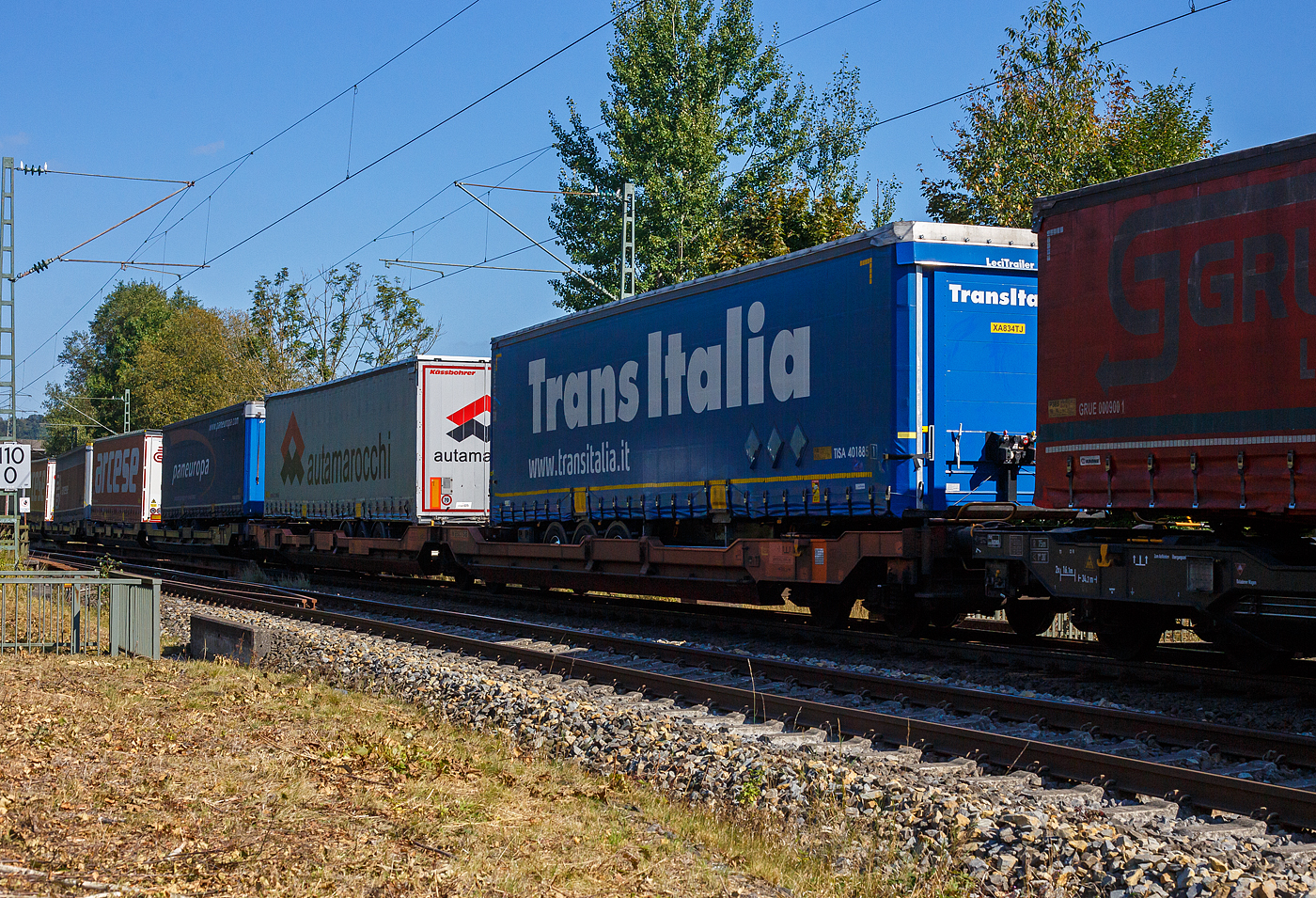 Sechsachsiger Gelenk-Taschenwagen (Doppeltaschenwagen T3000e), 37 85 4956 158-1 CH-WASCO, der Gattung Sdggmrss (T3000e), der WASCOSA AG, am 21 September 2024 im Zugverband bei der Durchfahrt in Siegen-Eiserfeld, hier beladen mit zwei Sattelanhängern (Trailer). 

Diese Wagen vom Typ T3000e wurde von Tatravagónka a.s. in Poprad (Slowakei) ab 2015 gebaut, die Entwicklung und Konstruktion ist von der Ferriere Cattaneo SA in Giubiasco (Schweiz). Baugleiche Wagen sind auch bei anderen Halteren im Einsatz, die jeweils die Gattungskennzahl 4956 haben. Mögliche Ladeeinheiten sind zwei kranmanipulierbare Sattelaufliegern oder alternativ bis zu vier Wechselbrücken und/oder Container in verschiedenen Längen (20′ bis 45′). Dafür besitzt der Wagen einen dreifach verstellbaren Stützbock sowie für die Ladungseinheiten feste und klappbare Aufsetzzapfen auf den Langträgern. Das maximale Zuladegewicht beträgt für Sattelauflieger 2 × 40 t; die Basishöhe liegt bei 270 mm über SO.

TECHNISCHE DATEN:
Spurweite: 1.435 mm (Normalspur)
Länge über Puffer: 34.200 mm
Drehzapfenabstand: 2 x 14.200 mm
Achsabstand in den Drehgestellen: 1.800 mm
Laufraddurchmesser: 920 mm (neu) / 860 mm (abgenutzt)
Drehgestelltyp: 1 x Y25Ls(s)i1f, 2 x Y25Lssi1-K
Ladelänge: 2 × 16.185 mm
Höhe der Ladefläche für Container: 1.155 mm
Eigengewicht: 34.300 kg
Max. Zuladung bei Lastgrenze S: 100,7 t (ab Streckenklasse D)
Max. Zuladung bei Lastgrenze SS: 85,7 t (ab Streckenklasse C)
Max. Geschwindigkeit: 100 km/h (bei Lastgrenze S) / 120 km/h (bei Lastgrenze SS und leer)
Bremse: 2 x DK-GP-A (K)
Bremssohle: Jurid 816 M
Radsatz: BA 004
Handbremse: am mittleren Drehgestell
Kleinster befahrbarer Kurvenradius: R 75 m (R 150 m im Zugverband)
Intern. Verwendungsfähigkeit: TEN  GE / G1

