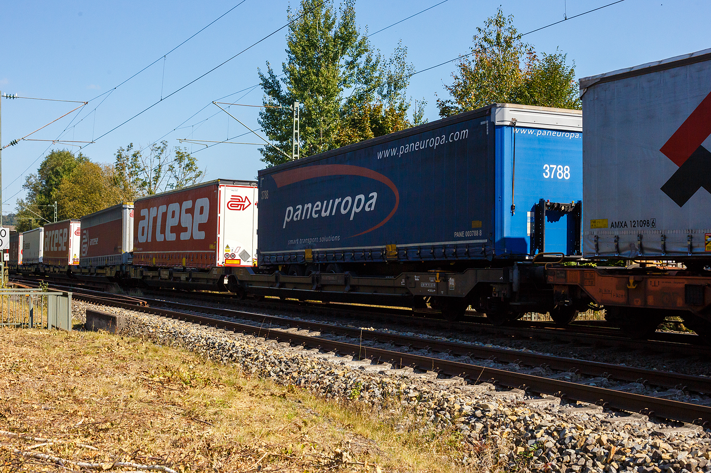 Sechsachsiger Gelenk-Taschenwagen (Doppeltaschenwagen T3000e), 37 85 4956 541-4 CH-TXL, der Gattung Sdggmrss (T3000e), der TX Logistik AG (Troisdorf), am 21 September 2024 im Zugverband bei der Durchfahrt in Siegen-Eiserfeld, hier beladen mit zwei Sattelanhängern (Trailer). Die TXL gehört seit 2017 zu 100 Prozent der Mercitalia Gruppe, einer Tochtergesellschaft der Ferrovie delle Stato Italiane.

Diese Wagen vom Typ T3000e wurde von Tatravagónka a.s. in Poprad (Slowakei) ab 2015 gebaut, die Entwicklung und Konstruktion ist von der Ferriere Cattaneo SA in Giubiasco (Schweiz). Baugleiche Wagen sind auch bei anderen Halteren im Einsatz, die jeweils die Gattungskennzahl 4956 haben. Mögliche Ladeeinheiten sind zwei kranmanipulierbare Sattelaufliegern oder alternativ bis zu vier Wechselbrücken und/oder Container. Dafür besitzt der Wagen einen dreifach verstellbaren Stützbock sowie für die Ladungseinheiten feste und klappbare Aufsetzzapfen auf den Langträgern. Das maximale Zuladegewicht beträgt für Sattelauflieger 2 × 40 t; die Basishöhe liegt bei 270 mm über SO.

TECHNISCHE DATEN:
Spurweite: 1.435 mm (Normalspur)
Länge über Puffer: 34.200 mm
Drehzapfenabstand: 2 x 14.200 mm
Achsabstand in den Drehgestellen: 1.800 mm
Laufraddurchmesser: 920 mm (neu) / 860 mm (abgenutzt)
Drehgestelltyp: 1 x Y25Ls(s)i1f, 2 x Y25Lssi1-K
Ladelänge: 2 × 16.185 mm
Höhe der Ladefläche für Container: 1.155 mm
Eigengewicht: 35.000 kg
Max. Zuladung bei Lastgrenze S: 100,0 t (ab Streckenklasse D)
Max. Zuladung bei Lastgrenze SS: 85,0 t (ab Streckenklasse C)
Max. Geschwindigkeit: 100 km/h (bei Lastgrenze S) / 120 km/h (bei Lastgrenze SS und leer)
Bremse: 2 x DK-GP-A (K)
Bremssohle: Jurid 816 M
Handbremse: am mittleren Drehgestell
Kleinster befahrbarer Kurvenradius: R 75 m (R 150 m im Zugverband)
Intern. Verwendungsfähigkeit: TEN  GE / G1
