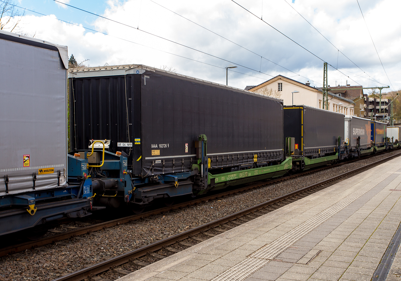 Spezieller sechsachsiger Gelenk-Taschenwagen System HELROM, 87 80 4993 003-3 D-HELR, der Gattung Sdmrs, der HELROM Trailer Rail am 28 März 2024 im Zugverband bei der Durchfahrt im Bahnhof Kirchen (Sieg).

Der Clou bei HELROM sind neuartige Transportwaggons, die keine teuren Kran- oder Verladeeinrichtungen brauchen. Auch müssen die Sattelauflieger nicht kranmanipulierbar sein, das sind auch hier zu Lande die wenigsten.
Dieses Megaswing-System ist ein spezieller Taschenwagen mit schwenkbaren Aufnahmewannen für Sattelauflieger. Hydraulikstützen dienen als Stabilisierung, wenn die Wanne nach links oder rechts ausschwenkt. Die Beladung der Wanne mit einem Sattelauflieger erfolgt rückwärts. Nach Absatteln des Sattelaufliegers wird die Wanne angehoben und schwenkt wieder ein. Der Sattelauflieger wird leicht abgesenkt und mit dem Waggon fest verbunden, er ist nun auf dem Waggon sicher verstaut. Die Technik ist im Waggon verbaut.

Wobei die beiden Sattelauflieger sind aber auch kranmanipulierbar, was man an den gelben Rechtecken erkennen kann.

TECHNISCHE DATEN:
Hersteller: Gök Yapi (Türkei)
Spurweite: 1.435 mm
Länge über Puffer: 34.230 mm
Drehzapfenabstand: 2 x 14.200 mm
Achsabstand im Drehgestellen: 1.800 mm
Laufraddurchmesser: 920 mm (neu)
Eigengewicht: 45.200 kg
Max. Zuladung bei Lastgrenze: 76,0 t (ab Streckenklasse D)
Max. Geschwindigkeit: 100 km/h (beladen) / 120 km/h (leer)
Kleinster befahrbarer Gleisbogen: R 75 m
Bremse: 2 x MH-GP-A (K)
Bremssohle: Cosid 810
Feststellbremse: Ja (aufs mittlere Drehgestell)
Intern. Verwendungsfähigkeit: TEN CW
