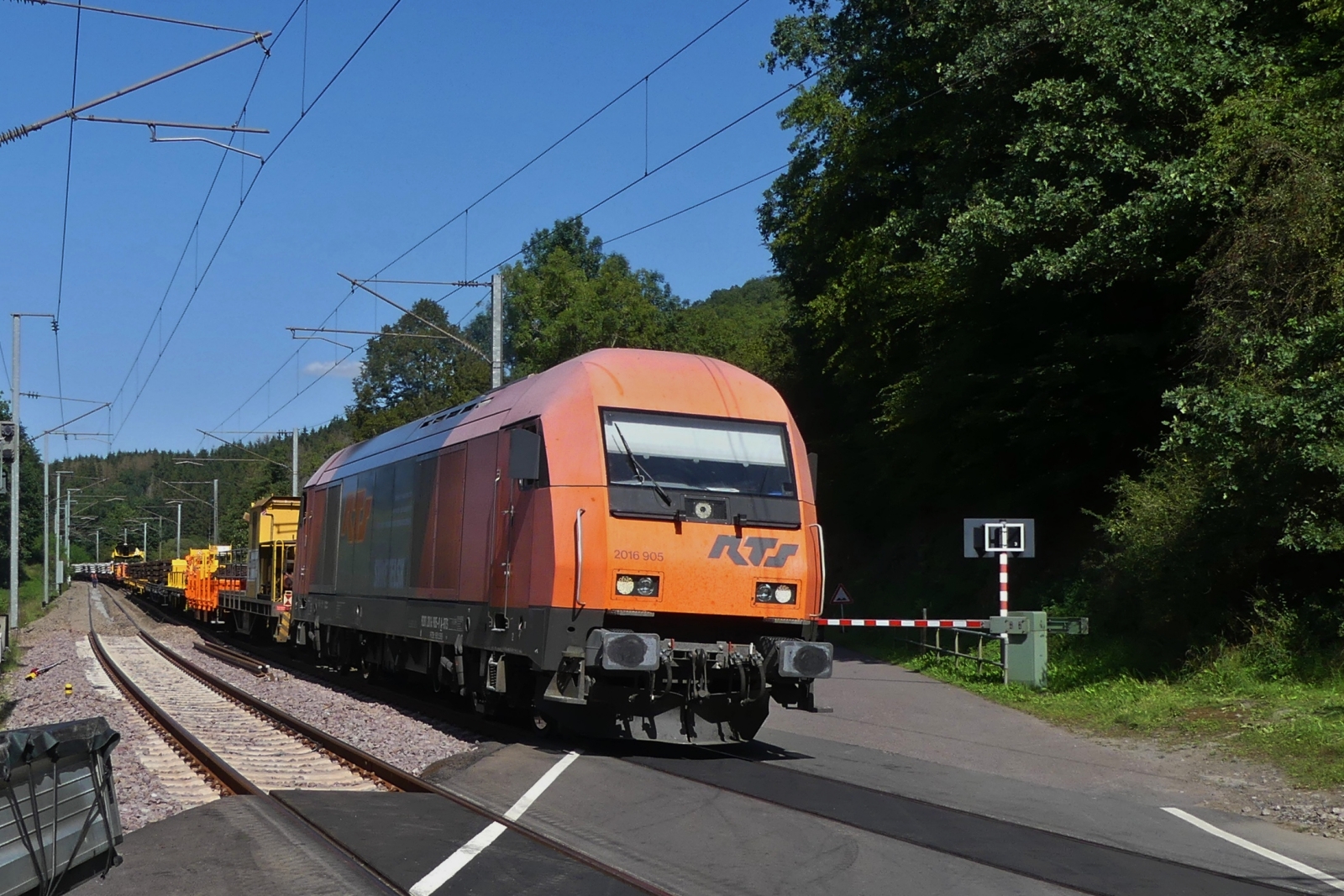 Um den Bahnübergang nicht zu lange zu blockieren wird die RTS Lok 2016 905 mit ein Paar Wagen vom Schienenbauzug getrennt, und fährt mit diesen über den Bahnübergang nahe Enscherange um den Bahnübergang für den Verkehr frei zu lassen. 23.08.2023