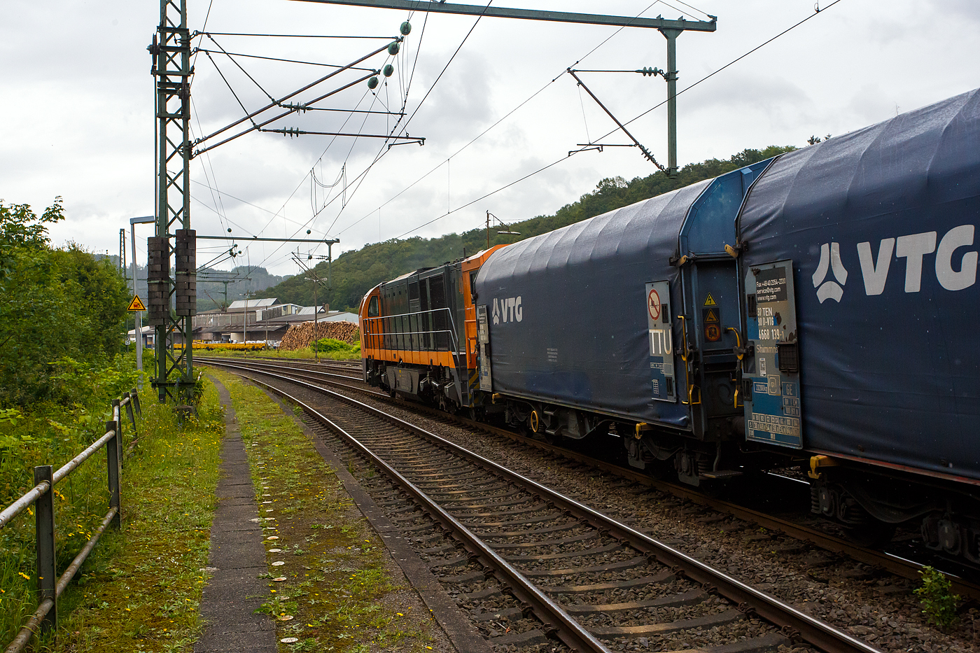 Und tschüss bis gleich in Herdorf, die KSW 43 (92 80 1273 018-2 D-KSW), die asymmetrische Vossloh G 2000 BB der KSW (Kreisbahn Siegen-Wittgenstein) fährt am 03 Juli 2024, mit einem beladen Coilzug (16 Stück VTG Coilwagen der Gattung Shimmns-ttu, VTG Bez. F46.520D) vom Hafen Duisburg kommend, durch den Bahnhof Scheuerfeld(Sieg) in Richtung Herdorf via Betzdorf. 

In Betzdorf (Sieg) geht es dann über KBS 462 „Hellertalbahn“ nach Herdorf zum Rbf der KSW (Betriebsstätte FGE -Freien Grunder Eisenbahn). Für die Weiterfahrt auf den Pfannenberg (in Neunkirchen-Salchendorf) über nimmt dort dann die KSW 47 (92 80 1271 027-5 D-KSW), ex D 2 der HFM, eine Vossloh G 1000 BB, den Zug.
