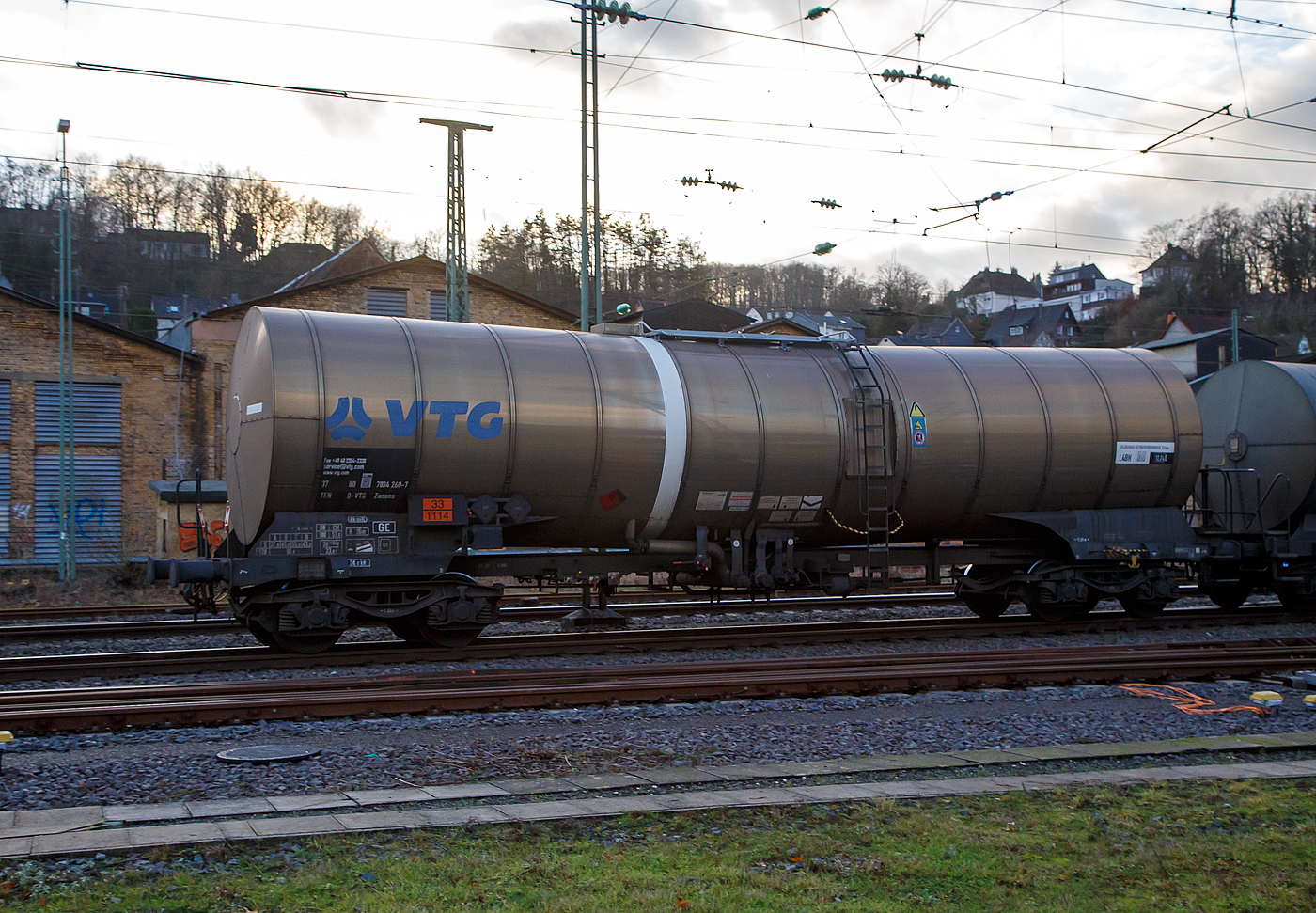 Vierachsiger 80 m³ Drehgestell-Kesselwagen, 37 80 7834 260-7 D-VTG, der Gattung Zacens (VTG-Bezeichnung M18.080D), der Waggonvermietungsfirma VTG AG (Hamburg) am 11.01.2023 im Zugverband bei einer Zugdurchfahrt in Betzdorf (Sieg). Die VTG ist Europas größter privater Waggonvermieter.

Das Ladegut (laut Gefahrgutnummer 33/1114) ist hier Benzol, eine flüssige organische Verbindung mit einem charakteristischen aromatischen Geruch. Die Verbindung ist ein aromatischer Kohlenwasserstoff und mischbar mit fast allen organischen Solventien, jedoch kaum mit Wasser. Benzol wird zur Herstellung wichtiger Industriechemikalien wie zum Beispiel Cyclohexan, Ethylbenzol und Nitrobenzol verwendet. Im Motorenbenzin sind in Deutschland und der EU nach EN 228 nur noch maximal ein Prozent erlaubt. Als Lösungsmittel wird Benzol nicht mehr verwendet, da es krebserregend ist.

Die Bedeutung der Gattungs- und Kennbuchstaben (hier Zacens):
Z - Kesselwagen für den Transport von flüssigen oder gasförmigen Erzeugnissen
a - mit vier Radsätzen
c - mit Entladung unter Druck
e - mit Heizeinrichtung
n - mit vier Radsätzen höchste Lastgrenze über 60 t
s - Höchstgeschwindigkeit 100 km/h (beladen)

TECHNISCHE DATEN:
Gattung: Zacens 
Spurweite: 1.435 mm
Länge über Puffer : 16.240 mm
Drehzapfenabstand: 11.200 mm
Achsabstand im Drehgestell: 1.800 mm
Laufraddurchmesser: 920 mm (neu)
Höchstgeschwindigkeit: 100 km/h / 120 km/h (leer)
Eigengewicht: 26.300 kg
Nutzlast: 55,7 t ab Streckenklasse C / 63,7 ab Streckenklasse D
Gesamtvolumen: 80.200 Liter (80 m³)
Max. Betriebsdruck: 3,0 bar
Tankcode: L 4 BH
L= Tank für Stoffe in flüssigem Zustand (flüssige Stoffe oder feste Stoffe, die in geschmolzenem Zustand zur Beförderung aufgegeben werden)
4= zutreffender Mindestprüfdruck in bar
B = Tank mit Bodenöffnungen mit 3 Verschlüssen für das Befüllen oder Entleeren 
H = luftdicht verschlossener Tank
Heizung: 6-strängig, außenliegend, 8 m³n Betriebsdruck 12,0 bar
Isolierung; Mineralwollfilz, 100 mm, Isolierabdeckung aus Edelstahl
Restmengenentleerung: Tankneigung von 1° und Sumpfmulde
Bremse: KE-GP-A (K)
Bremssohle: C810
Intern. Verwendungsfähigkeit: TEN-GE
