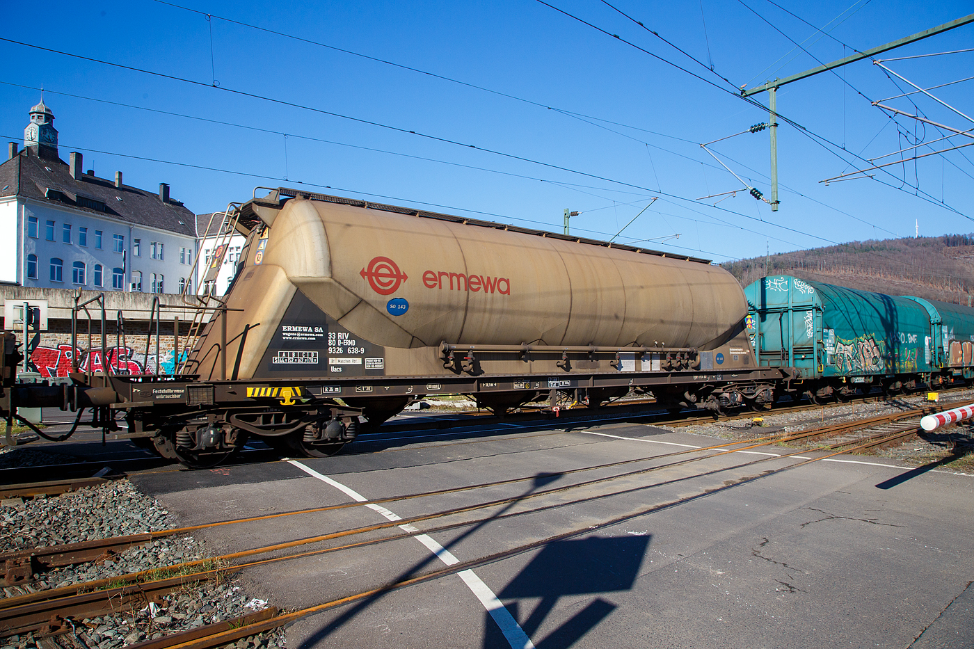 Vierachsiger 80m³ Silowaggon bzw. Drehgestell-Staubgutwagen für SO 143 – Aluminiumoxid 33 80 9326 673-6 D-ERMD, der Gattung Uacs (Type 6924 B0), französischen Vermietungsfirma ERMEWA S.A., im Zugverband am 14.02.2023 bei der Zugdurchfahrt in Niederschelden (Sieg).

Der Wagen wurde (ca. 1998) von der Waggonbau Graaff GmbH (Tochterunternehmen der VTG) gebaut, der Oberbau (Silobehälter ist von der Feldbinder Spezialfahrzeugwerke GmbH.

TECHNISCHE DATEN:
Spurweite: 1.435 mm
Länge über Puffer : 18.100 mm
Drehzapfenabstand: 13.070 mm
Achsabstand im Drehgestell: 1.800 mm
Höchstgeschwindigkeit: 100 km/h
Gesamtvolumen: 80 m³ (80.000 l)
Eigengewicht: 19.100 kg
Nutzlast: 70,9 t (ab Streckenklasse D)
zul. Gesamtgewicht: 90,00 t
Max. Betriebsdruck: 2,50 bar
Kleinster bef. Halbmesser: 36 m
Bremse: KE-GP-A (LL)
Bremssohle: IP 116
Intern. Verwendungsfähigkeit: RIV
