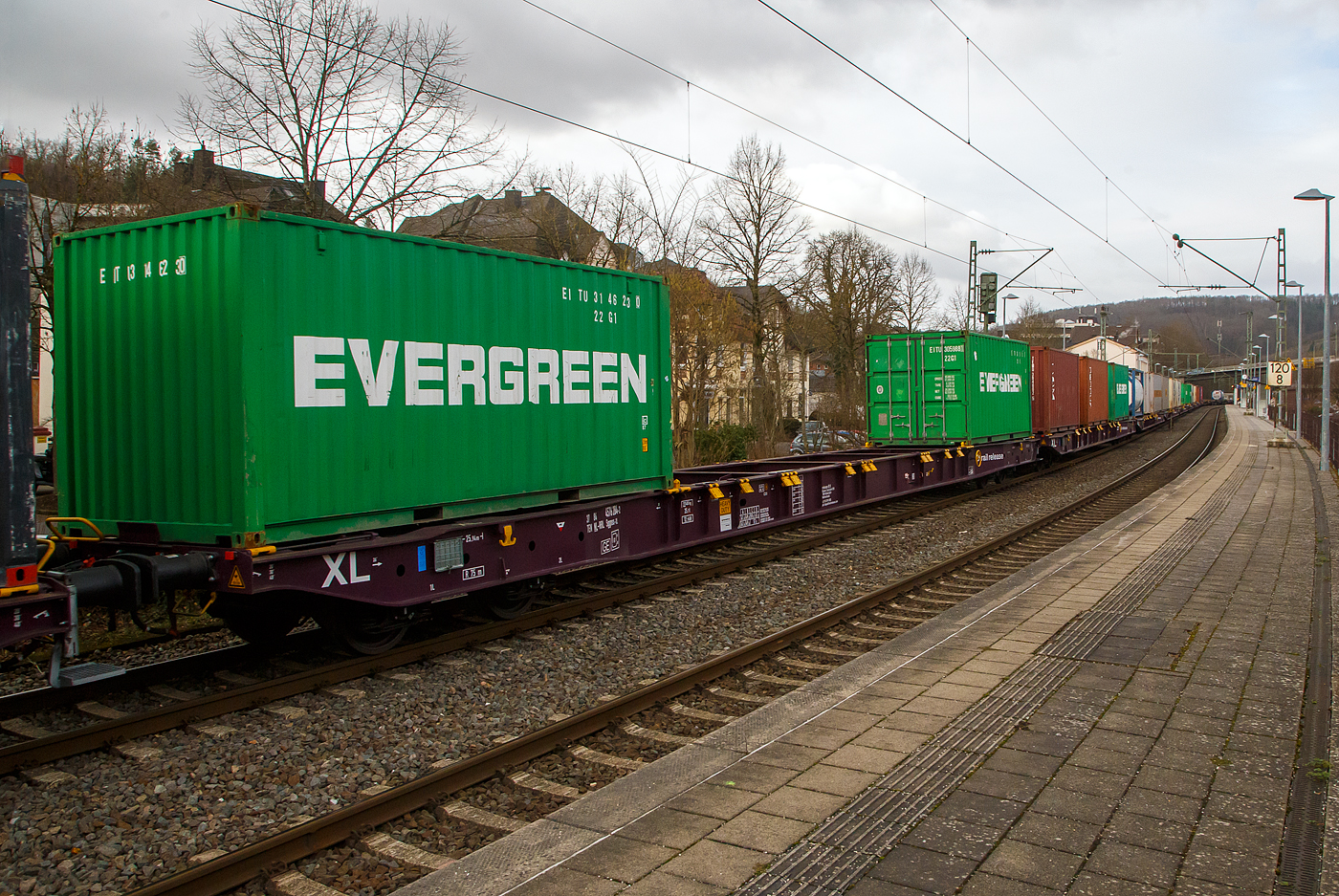 Vierachsiger Drehgestell-Containertragwagen 37 84 4576 284-2 NL-RRL, der Gattung Sggnss-xl (Sggnss 80’XL), der niederl�ndischen Vermietungsfirma RailRelease B.V. (Rotterdam), am 04.02.2023 im Zugverband bei der Zugdurchfahrt im Bahnhof Kirchen (Sieg). Hier beladen mit zwei 20ft-Container.

Der Wagen wurde Tatravagonka Poprad (Slowakei) gebaut, das Baujahr konnte ich nicht erkennen. Mit dem Containertragwagen der Bauart Sggnss 80´ ist es erstmals m�glich Container mit einer Gesamtl�nge von 80 Fu� auf einem vierachsigen Drehgestellwagen zu transportieren. Der Wagen hat eine L�nge von 25.940 mm. 

Der LIGHT EIGHTY Sggnss-xl wurde von TATRAVAG�NKA schon 2010 auf Veranlassung von METRANS entwickelt. Nicht nur dank seinem geringen Gewicht von 22,4 t, sondern auch wegen den einzigartigen Ladem�glichkeiten (5 Container�Bauarten und Wechselaufbauten in 30 verschiedenen Containerkombinationen) hat sich dieser Wagen schnell auf dem Markt etabliert. Im Vergleich zum 80’ langen Standardwagen kann bei dieser Variante ein Wagen mehr in G�terz�ge aufgenommen werden. Durch die neuartige Konstruktion dieses TSI�‐konformen Wagens konnte nicht nur der L�rmpegel auf einen Messwert von 78 dB(A) reduziert werden. Eine Energieeinsparung von 20 % im Vergleich zum 80’-langen Standardgelenkwagen erm�glicht eine weitere Steigerung der Transporteffizienz. Weniger Drehgestellbedarf bedeutet weniger Instandhaltungsaufwand f�r Bremssysteme.

TECHNISCHE DATEN:
Spurweite: 1 435 mm
Anzahl der Achsen: 4 in zwei Drehgestellen
L�nge �ber Puffer: 25.940 mm
Drehzapfenabstand: 19.300 mm
Achsabstand im Drehgestell: 1.800mm
Laufraddurchmesser: 920 mm (neu)
Drehgestell- und Laufradtyp: Y25Ls1-K  / Ba303
Ladel�nge : 24 700 mm  (z.B. 2 x 40’ ISO Container)
H�he der Ladeebene �ber SOK: 1.155 mm
H�chstgeschwindigkeit: 100 km/h, bei Lastgrenze SS und leer 120 km/h
Max. Zuladung bei Lastgrenze S: 67,6 t (ab Streckenklasse D)
Max. Zuladung bei Lastgrenze SS: 57,6 t (ab Streckenklasse C)
Eigengewicht: 22.400 kg
Kleinster bef. Gleisbogenradius: R 75 m (150 m im Zugverband)
Bauart der Bremse: KE-GP-A (K)
Bremssohle: C 333 (CoFren, gesintert)
Handbremse: Ja
Intern. Verwendungsf�higkeit: TEN-GE