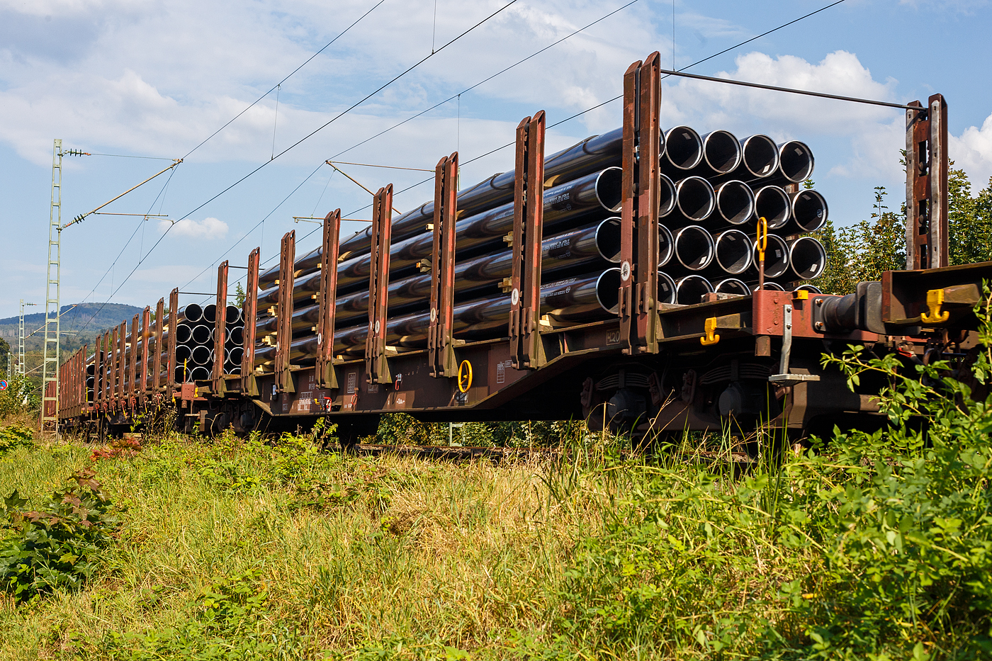 Vierachsiger Drehgestell-Flachwagen mit 8 Doppelrungenpaaren mit integrierter Niederbindeeinrichtung, 31 80 4723 xxx-x D-DB, der Gattung Snps 719.1, der DB Cargo AG, am 19 September 2024 im Zugverband bei einer Zugdurchfahrt im Bahnhof Kirchen (Sieg). Hier beladen mit HFI-längsnahtgeschweißte Stahlrohre Ø 323.9 (DN/NW 300 mm bzw. 12 ¾ Inch) in Herstellungslänge vom 12 m. Der Hersteller der Stahlrohre ist die Salzgitter Mannesmann Line Pipe GmbH in Siegen (ex RW Fuchs).

Der Drehgestell-Flachwagen wurde speziell für den Transport von Rohren, Profilstahl, Flachstahlprodukten sowie Stamm- und Schnittholz entwickelt und zeichnet sich durch hohe Ladekapazität aus. Das Ladegut wird durch Rungen mit Schichtholzleisten und Kunststoffspitzen geschont (nur bei BA 719.1 Stahlhalbzeuge. Wird bei der BA 719.0 Timber (Holz) nicht benötigt und ist daher auch nicht montiert.). Die Längsseiten sind jeweils mit acht besonders breiten und belastbaren Rungen ausgerüstet, die mit dem Untergestell fest verbunden sind. Zur Verzurrung des Ladegutes ist jedes Rungenpaar mit einer Niederbindeeinrichtung versehen, die von einer Person bedient werden kann. Die Wagen wurden ab 1980 als Sps 719 beschafft und ab 1988 in Snps 719 umgezeichnet.

Zur Aufnahme und Abstützung der Ladung sind auf dem Wagenboden Ladeschwellen und an den Wagenlängsseiten Rungen angebracht. Zur Verzurrung der Ladung sind von Hand zu bedienende Niederbindeeinrichtungen vorhanden. Für die Auflage des Ladegutes sind hölzerne Ladeschwellen im Rungenbereich und im Abstand von 1 m von Wagenende vorhanden. Außerdem sind feste 5 mm niedrigere Hilfsladeschwellen zwischen den Rungen zur Unterstützung von leicht durchhängendem Ladegut (z. B. Schnittholz) angeordnet. Die Ladeschwellen sind genügend hoch, so dass die handelsüblichen Umschlagmittel verwendet werden können. Der Wagenboden ist mit einem begehbaren Loch- bzw. Riffelblech vollständig abgedeckt. Zur Aufnahme von Lasten oder zum Befahren mit Flurförderfahrzeugen sind die Abdeckungen nicht geeignet. Zur Sicherung der Ladung sind auf jeder Wagenlängsseite in gleichmäßigen Abständen 8 Rungen vorhanden. Die Rungen sind mit dem Untergestell-Außenlangträger fest verbunden und so ausgeführt, dass sie die durch die Ladung entstehenden Kräfte in Wagenlängs- und Wagenquerrichtung sicher aufnehmen können. Die Innenseiten der Rungen sind ausgekleidet.

Zur Verzurrung des Ladegutes ist jedes Rungenpaar mit einer Niederbindeeinrichtung ausgerüstet, die von einer Person bedient werden kann. Die Spanngurte sind zur Schonung des Ladegutes mit einem elastischen Werkstoff ummantelt. Die Länge des Gurtes und die Teilung der Raster sind so gewählt, dass auch Ladungen, die nur etwa die halbe Rungenhöhe einnehmen, verzurrt werden können.

TECHNISCHE DATEN:
Gattung: Snps 719.1
Spurweite: 1.435 mm (Normalspur)
Länge über Puffer: 20.840 mm
Drehzapfenabstand: 15.800 mm
Radsatzstand in den Drehgestellen: 1.800 mm
Ladelänge: 19.000 mm
Ladebreite: 2.723 mm (zwischen den Rungen)
Fußbodenhöhe über SO: 1.280 mm (OK Ladeschwelle)
Rungenhöhe: 2.000 mm
Eigengewicht: 24.400 kg
Zuladung bei Lastgrenze S: 63 t (ab Streckenklasse D)
Max. Geschwindigkeit: 100 km/h / 120 km/h (leer)
Kleinster Gleisbogenhalbmesser: 35 m
Bauart der Bremse: KE-GP (LL)
Bremssohle: IP 116
Handbremse: Ja
Verwendungsfähigkeit: RIV