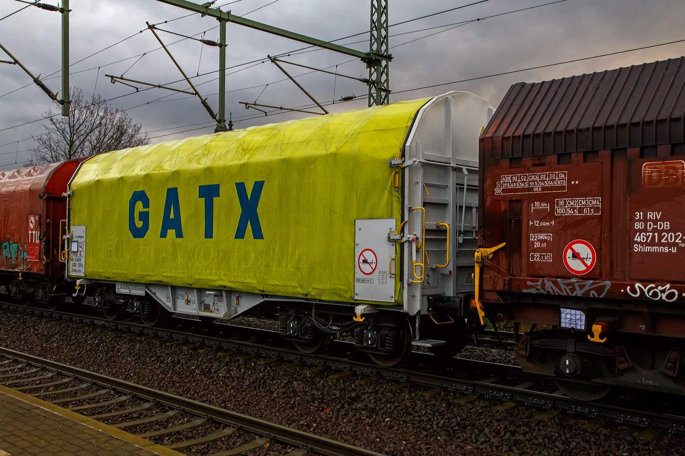 Vierachsiger Drehgestell-Flachwagen mit verschiebbarem Planenverdeck und Lademulden für Coiltransporte, 37 80 4668 599-6 D-GATED, der Gattung Shimmns-ttu, der GATX Rail Germany GmbH, am 07.12.2022 im Zugverband bei einer Zugdurchfahrt im Bahnhof Dresden-Strehlen. Der Waggonvermieter GATX (General American Transportation Corporation) ist eine US-amerikanische Leasinggesellschaft für Schienenfahrzeuge mit Sitz in Chicago. GATX wurde 1898 gegründet und ist seit 1916 an der New Yorker Börse notiert.

Diese Wagen sind speziell für den Transport witterungsempfindlicher Blechrollen (Coils) bestimmt. Er besitzt feste Stirnwände, 5 fest im Untergestell eingebaute Lademulden. Die Wagenabdeckung erfolgt mit einer PVC-beschichteten Gewebeplane, die auf 11 Rohrrahmen aufliegt. Über Laufwagen ist das Planendach in Wagenlängsrichtung verschiebbar. Die Verriegelung des Planendaches an den Stirnwänden erfolgt über eine 4-Punkt-Zentralverriegelung, die sowohl vom Erdboden als auch von der Rampe aus bedient werden kann. Das Planenverdeck lässt sich an einem Wagenende so weit zusammenschieben, dass ca. 2/3 der Ladefläche zur Beladung freigegeben wird. Hierdurch ist eine einfache Beladung des Wagens sowohl von oben als auch von der Seite aus möglich. 

TECHNISCHE DATEN:
Spurweite: 1.435 mm
Achsanzahl: 4 (in 2 Drehgestelle)
Länge über Puffer: 12.040 mm
Länge der Ladefläche: 10.800 mm
Drehzapfenabstand: 7.000 mm
Achsabstand im Drehgestell: 1.800 mm
Eigengewicht:  21.770 kg
Höchstgeschwindigkeit: 100  km/h (beladen) / 120 km/h (leer)
Maximales Ladegewicht: 68,2 t (Streckenklasse D4)
Kleinster bef. Gleisbogenradius: 35 m
Bauart der Bremse: KE-GP-A (K)
Bremssohle: C 810
Intern. Verwendungsfähigkeit: TEN - GE