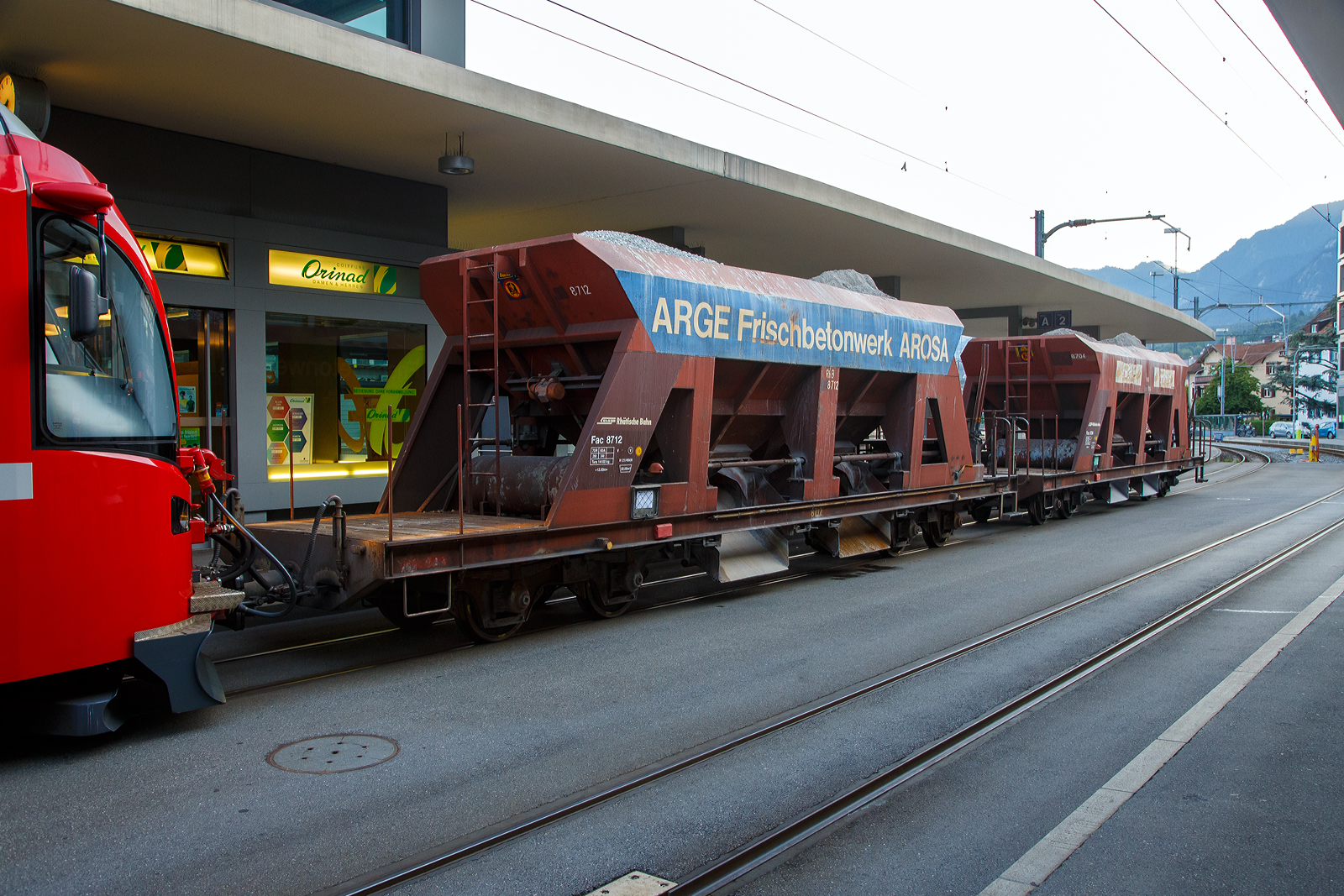 Vierachsiger Drehgestell-Schotterwagen (Schwerkraftentladewagen) RhB Fac  8712 (der Serie 8701 – 8712), eingereiht in einen RhB PmG (Personenzug mit Güterbeförderung) nach Arosa, geführt von dem ALLEGRA-Zweispannungstriebzug RhB ABe 8/12 -3507 „Benedetg Fontana“ am 07 September 2021 am Bahnhofvorplatz in Chur.

Diese Wagen wurden 1968 und 1971 von der Firma Josef Meyer in Rheinfelden gebaut. Mit den Schwerkraftentladewagen transportiert die RhB problemlos Ihre Schüttgüter wie Kies, Sand etc. auf der Schiene durch Graubünden. Ein rascher Verlad und Entlad spart Zeit und Geld und mit 33 – 34 Tonnen Ladung ist es eine gewichtige Alternative zum Straßentransport. Die Wagen haben je zwei Entladungsöffnungen längsseits, die Auslaufmenge ist dosierbar.

TECHNISCHE DATEN:
Spurweite: 1.000 mm
Länge über Puffer: 12.500 mm
Breite über Alles: 2.550 mm
Höhe über SOK: 3.360 mm
Drehzapfenabstand: 7.000 mm 
Achsabstand im Drehgestell: 1.400 mm
Laufraddurchmesser: 750 mm (neu)
Breite der Entladeöffnungen: 2 x 1.232 mm
Eigengewicht: 14.100 kg
Ladegewicht: max. 34 t
Ladevolumen: 22 m³
Breite der Entladeöffnungen: 2 x  1.232 mm