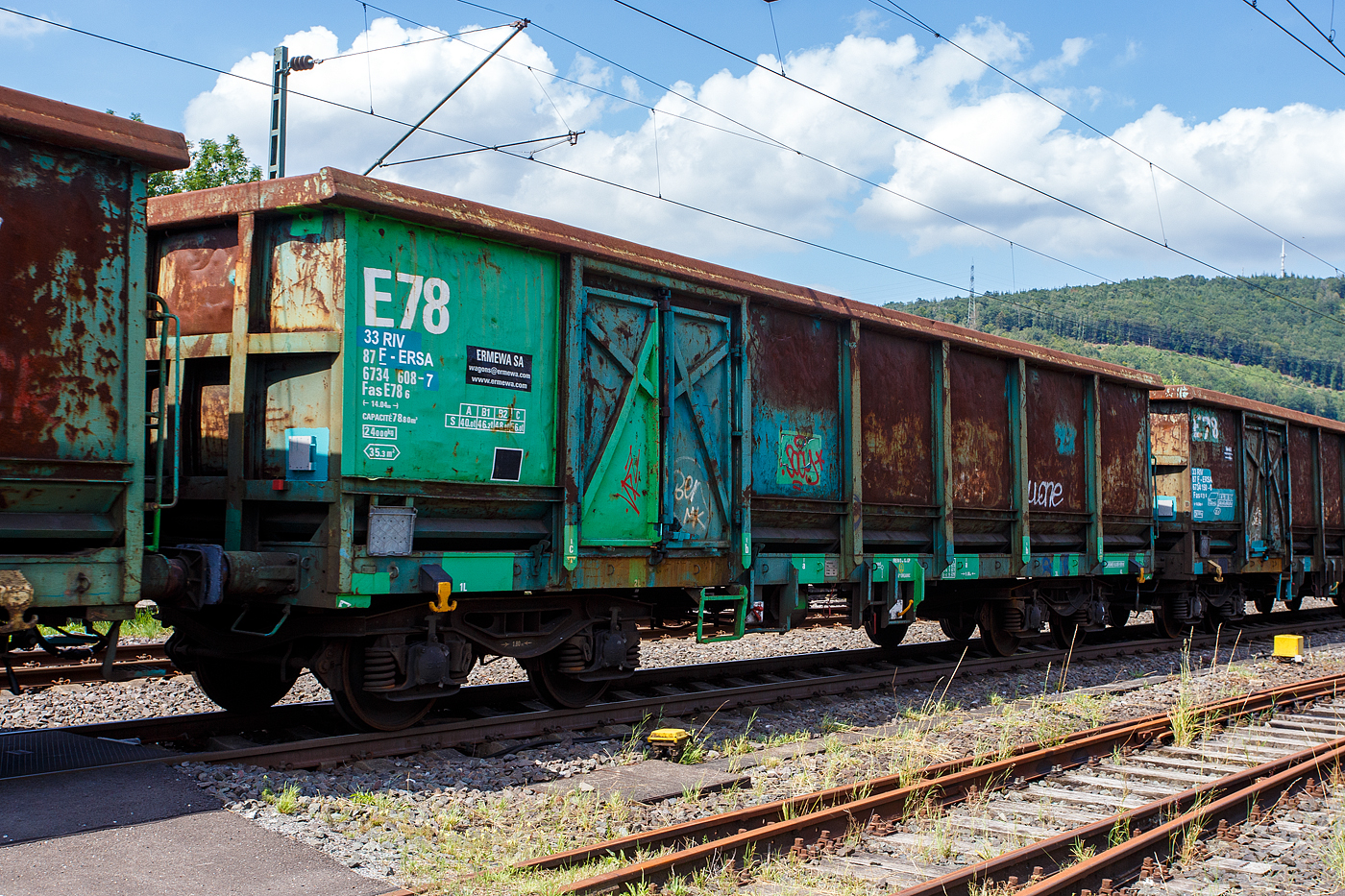 Vierachsiger offener G�terwagen E 78 in Sonderbauart, 33 87 6734 606-7 F-ERSA, der Gattung Fas E78 6, der franz�sischen Vermietungsfirma ERMEWA SA, am 22 Juli 2024 im Zugverband bei einer Zugdurchfahrt in Niederschelden.

Die Gattung Fas ist eine Weiterentwicklung der Gattung Eaos (Offene G�terwagen in Regelbauart) mit verst�rktem Wagenkasten und Bodenblech. Die Wagen besitzen einen Fu�boden aus 12 mm dicken Stahlblech und haben einen durchgehenden Obergurt, zudem sind Bindem�glichkeiten f�r Wagendecken vorhanden. Dioe Wagen sind speziell f�r den Transport von Stahlschrott, Holzhackschnitzel, Sch�ttg�ter mit K�rnung gr�sser 20 mm konzipiert. Die Be-, und Entladung vom Ladegut kann auf �blicher Art und Weise (Elektromagnet, Greifer, et.) durchgef�hrt werden.

Bedeutung der Gattungs- und Kennbuchstaben:
F = Offener Wagen in Sonderbauart
a = Mit 4 Rads�tzen
s = H�chstgeschwindigkeit 100 km/h (beladen nach Lastgrenzraster)

TECHNISCHE DATEN der Fas:
Spurweite: 1.435 mm (Normalspur)
Anzahl der Achsen: 4 (in 2 Drehgestellen)
L�nge �ber Puffer: 14.040 mm
Drehzapfenabstand: 9.000 mm
Achsabstand im Drehgestell: 1.800 mm
Drehgestellbauart: Y25 Csm (SIG)
Laufraddurchmesser: 920 mm (neu)
Ladefl�che: 35,3 m�
Laderaum:  73,8 m�
Ladel�nge: 12.800 mm
T�r�ffnung (1 je L�ngsseite): 1.800 x 1.800 mm
Eigengewicht: 24.000 kg 
H�chstgeschwindigkeit: 100 km/h (beladen gem. Lastgrenzraster) / 120 km/h (leer)
Max. Ladegewichte: 56,0 t ab Streckenklasse C
Kleinster bef. Gleisbogenradius: 50 m
Bremse: Frein O ou (oder) Ch-Gp (LL)
Bremssohle: IB 116
Handbremse: teilweise
Intern. Verwendungsf�higkeit: RIV