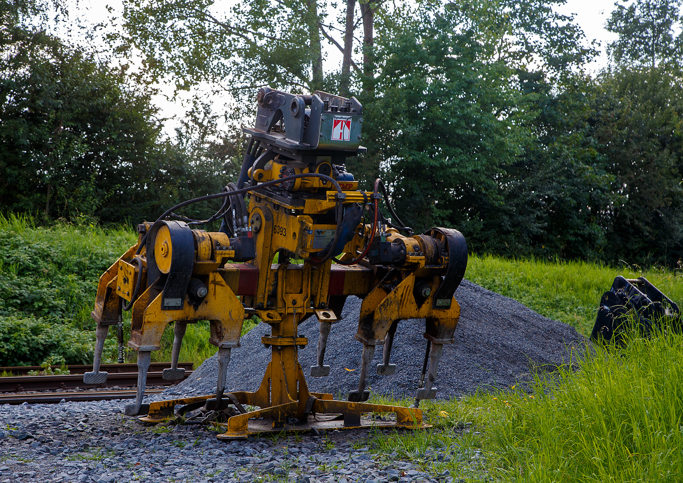 Windhoff Anbaustopfgerät ASTUW mit Liebherr LIKUFIX 33-9 vollautomatischen Schnellwechselsystem für den Anbau an einen Zweiwegebagger, der Firma W. Hundhausen Bauunternehmung GmbH, Siegen, abgestellt (auf Ständer) am 26.08.2023 in Herdorf beim Lokschuppen der KSW, Betriebsstätte FGE -Freien Grunder Eisenbahn.

Das Gerät 2019 wurde von der WINDHOFF Bahn- und Anlagentechnik GmbH in Rheine unter der Auftragsnummer 101109977 gebaut.

Das Anbaugerät besitzt zwei Arbeitsaggregate mit insgesamt 8 Stopfpickeln, die bei Arbeiten im Gleis gleichzeitig in den Schotter eintauchen. Für Einsätze in Weichen kann je nach Bedarf ein Arbeitsaggregat hydraulisch hochgeschwenkt werden. Der max. hydraulische Betriebsdruck beträgt 150 bar bei einer konstanten Förderleistung von  75 l/min. Das Anbaugerät wiegt ca. 1.680 kg. 

Das Schnellwechselsystem LIKUFIX 33-9 ist ein vollautomatisches Schnellwechselsystem von Liebherr. So können hydraulische Anbauwerkzeuge wie beispielsweise Stopfgeräte im Gleisbau, Mulcher mit Klappen oder Stielverlängerungen schnell, einfach und vor allem sicher aus der Fahrerkabine heraus gewechselt werden.
