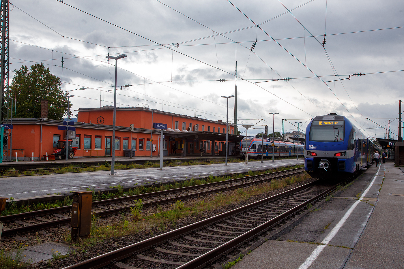 Wir haben mit den beiden sechsteiligen Stadler  FLIRT�  der Baureihe 1430 (ET 316 und ET 327) der BRB -Bayerische Oberlandbahn GmbH (Chiemgau-Inntal), als RE 5 Salzburg – M�nchen, am 11.09.2022 den Bahnhof Freilassing erreicht. Wir hatten unsere Ausweise zur Hand und durften direkt aussteigen, denn im Bahnhof Freilassing finden derzeit Grenzkontrollen stand. 

Der Bahnhof Freilassing ist ein Eisenbahnknoten im S�dosten von Bayern an den Strecken Rosenheim–Salzburg, M�hldorf–Freilassing und Freilassing–Bad Reichenhall. Er liegt auf dem Gebiet der Stadt Freilassing im Landkreis Berchtesgadener Land. Als letzter deutscher Bahnhof an der Strecke nach Salzburg ist er Grenzbahnhof nach �sterreich und verf�gt �ber neun Bahnsteiggleise.

Die K�niglich Bayerischen Staatseisenbahnen nahmen den Bahnhof 1860 mit der Strecke Rosenheim–Salzburg in Betrieb. Mit der Er�ffnung der Strecke nach Bad Reichenhall 1866 wurde er zum Trennungsbahnhof, mit Er�ffnung der Lokalbahn von Laufen 1890 schlie�lich zum Knoten. Von 1905 bis 2002 existierte in Freilassing ein Bahnbetriebswerk, dessen Gel�nde seit 2006 durch das Eisenbahnmuseum Lokwelt Freilassing genutzt wird. 