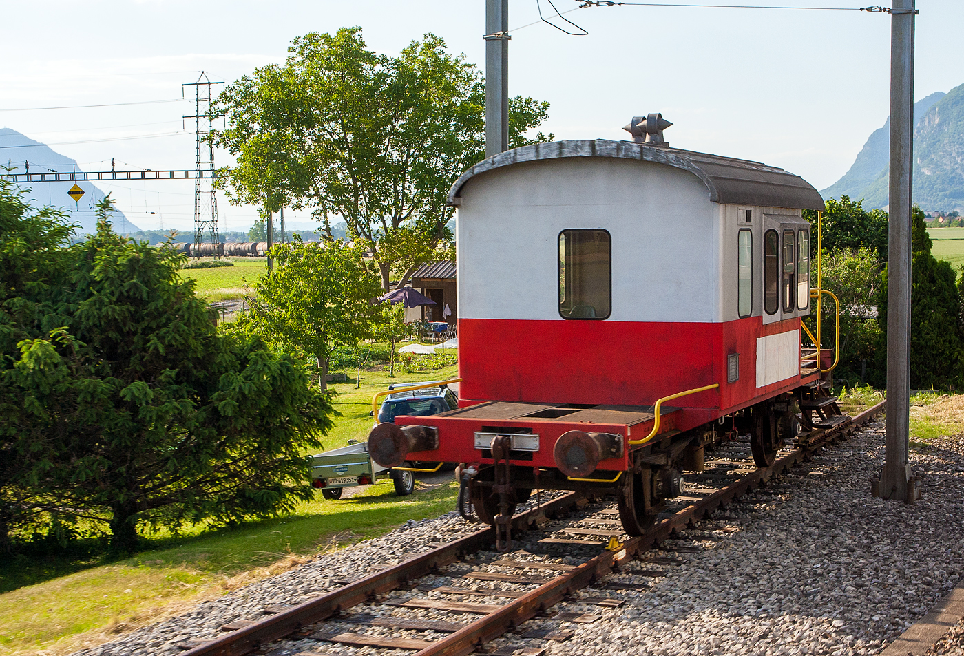 Zweiachsiger G�terzugbegleitwagen „Sputnik“ abgestellt auf einem Abstellgleis am 28 Mai 2012 in Saint-Triphon (VD), aufgenommen aus einem Zug heraus.

Diese Wagen wurden urspr�nglich als Dienstbegleitwagen Db 60 85 99-29 xxx-x bezeichnet, wegen der Beobachtungsfunktion am Zugschluss von G�terz�gen wurde sie von den Eisenbahnern „Sputnik“ genannt. Ende der 1980er wurden sie zum Dienstwagen (B�rowagen) Xs 40 85 95 35 xxx-x um bezeichnet. Die SBB Wagen waren urspr�nglich im damaligen SBB-Gr�n lackiert. Der Wagen hier ist in der  Swiss-Express  Lackierung, er wurde ggf. zuletzt als Kuppelwagen f�r die �berf�hrung einzelner EW III mit Mittelpufferkupplung eingesetzt. Da sich hier keine Beschriftungen (sind �bermalt) an dem Wagen befinden, kann ich nicht sagen ob es sich um einen SBB oder BLS Wagen handelt.

Ab 1957 bauten die SBB im Werk Chur in mehreren Serien auf Untergestellen abgebrochener Personenwagen insgesamt 385 St�ck dieses zweiachsigen Dienstbegleitwagens der Gattung Db. In Anspielung auf die Beobachtungsfunktion wurden die Wagen von den Eisenbahnern als „Sputnik“ genannt. Die BLS baute f�r den eigenen Bedarf ebenfalls sechs Sputniks. Wegen des kurzen Achsstandes von nur 5 Metern bei einer L�nge von 9,24 m und des geringen Gewichtes von 10 t wurde das Zugpersonal bei schneller Fahrt (max. 100 km/h) im Aufenthaltsraum und am Beobachtungsposten regelrecht durchgesch�ttelt. 

Ausgestattet war der Wagen mit Einrichtungsgegenst�nden ausrangierter Personenwagen. So fand man in dem auf ein Wagengestell aufgesetzten H�uschen eine WC-Kabine ohne Sp�lung, aber mit einem Wasserk�bel, eine doppelte Holzbank aus der dritten Klasse und einen Gasofen mit Ofenrohr. Die Gasflaschen befanden sich auf einer der Plattformen in einem Kasten, welcher dem Zugpersonal auch als Sitz an der frischen Luft dienen konnte. Der Wagen lief grunds�tzlich am Zugschluss. Mit dem Abbau der Begleitung von G�terz�gen wurde der Bestand reduziert und Anfang der 1990er Jahre endete der Einsatz. Sputnik-Wagen wurden auch f�r andere Zwecke adaptiert, beispielsweise als Kuppelwagen f�r die �berf�hrung einzelner EW III mit Mittelpufferkupplung.

TECHNISCHE DATEN:
Spurweite: 1.435 mm (Normalspur)
Anzahl der Achsen: 2
L�nge �ber Puffer: 9.240 mm
Drehzapfenabstand: 5.000 mm
Eigengewicht: ca. 10.000 kg
Nutzlast: 0 t 
H�chstschwindigkeit: 100 km/h
Bauart der Bremse: Dr-P (10 t)