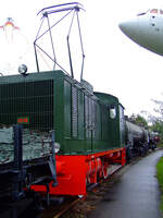 Nein keine E-Lok, sondern eine Diesellok, der Stromabnehmer diente zur Steuerung von Signalen...

Die ehemalige Lok 2018 der Stadtwerke Frankfurt (Taunusbahnen) eine BMAG LDF 300 C12 (abgespeckte V 36) am 02.10.2010 im Technik Museum Speyer.

Die Lok wurde 1939 von der Berliner Maschinenbau-Actien-Gesellschaft vormals L. Schwartzkopff (BMAG) unter Fabriknummer 10865 gebaut und an die Pulverfabrik Wolff & Co. KG aA in Walsrode als Lok 13 geliefert. Bereits 1943 ging sie an die Dortmund-H�rder H�ttenverein AG. Ende 1952 ging sie an die Sch�ma - Christoph Sch�ttler Maschinenfabrik GmbH in Diepholz, dort erfolgten umfangreiche Umbauten u. a. neuer Motor vom Typ MWM TRHS 526 S und neue Druckluftanlage. Dann ging sie 1954 an die St.M.B. - Steinhuder Meer-Bahn GmbH, als Lok 271. Mitte 1962 ging sie an die Stadtwerke Frankfurt als Lok 2018 und erhielt dort, zur Steuerung von Signalen auf der Strecke der ehemaligen Frankfurter Lokalbahn, Stromabnehmer. Die Lokomotive wurde 1980 wegen eines Risses im Motorblock abgestellt und an die Historische Eisenbahn Frankfurt abgegeben. Zum Technik Museum Speyer kam die Lok im Jahr 2000.
  	  	
Die Lok wird oft als WR 360 C 14 (V 36) Vorserienexemplar beschrieben, welches sie aber nicht ist. Die BMAG entwickelte aus der WR 360 C12 (Vorserien V36) eine 300 PS-Lokomotive f�r den industriellen Einsatz. Motorisiert wurde die Lok mit einem 8-Zylinder-Deutz-Motor des Typs A8M324. Bei nahezu gleichen Abmessungen wurden folgende Anpassungen gegen�ber der WR 360 C12 vorgenommen:

• �bersetzung im mechanischen Teil des Getriebes ge�ndert; Vmax 25 km/h; Zugkraft 12.000 kg
• Im F�hrerstand beidseitig vorhandene Handr�der f�r einm�nnige Bedienung der Lok
• Verzicht auf Doppeloksteuerung (u. a. keine �bergangst�re im F�hrerstand)

Von dieser Type wurden vier Exemplare gebaut, die alle an die Pulverfabriken Wolff & Co. in Walsrode ausgeliefert wurden.

Die WR 360 C12 hatte gegen�ber der V 36 (WR 360 C14) kein Stufengetriebe und war um 350 mm k�rzerer.
