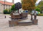 
Auf dem Bahnhofsvorplatz von Diekirch ist diese Bronzeskulptur von einem Dampfzug mit darum herum spielenden Kindern aufgestellt. 
Aufnahme vom 14.09.2014.